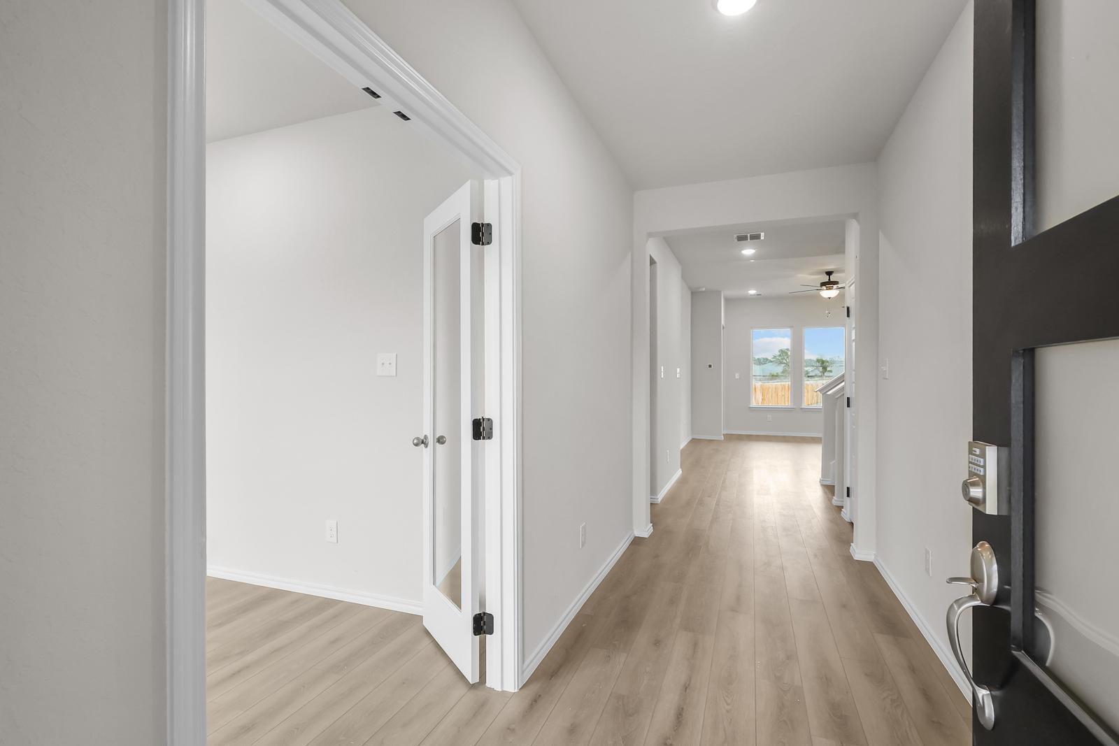 Bright foyer and entryway of The Sequoia C in Converse, Texas, featuring wood-look flooring and a glass-paneled den door.