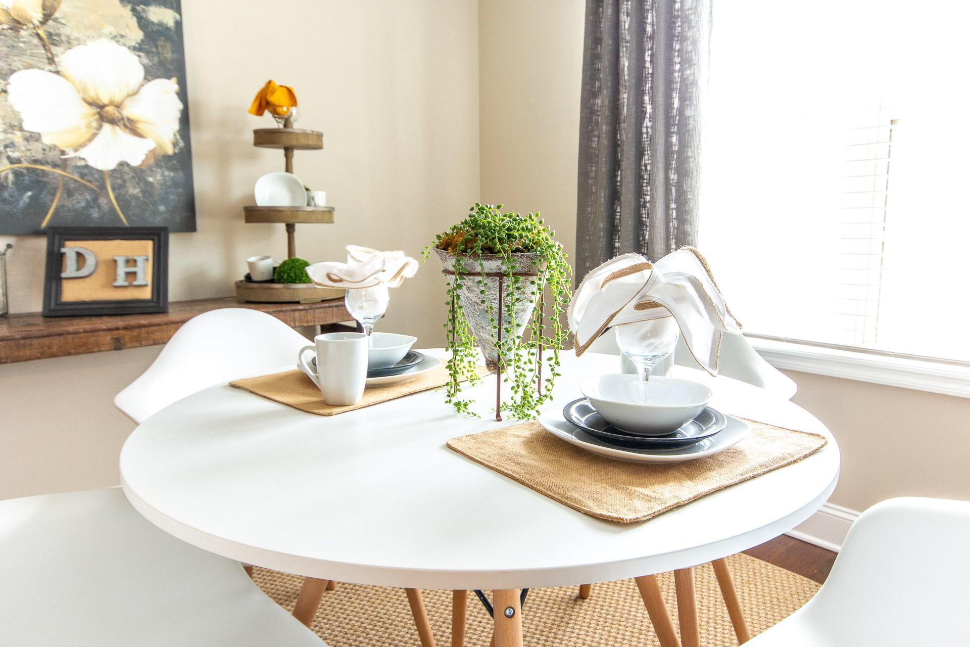 Modern dining nook at Summer Pointe in Madison Alabama with round white table, set plates, cups, and hanging succulent plant