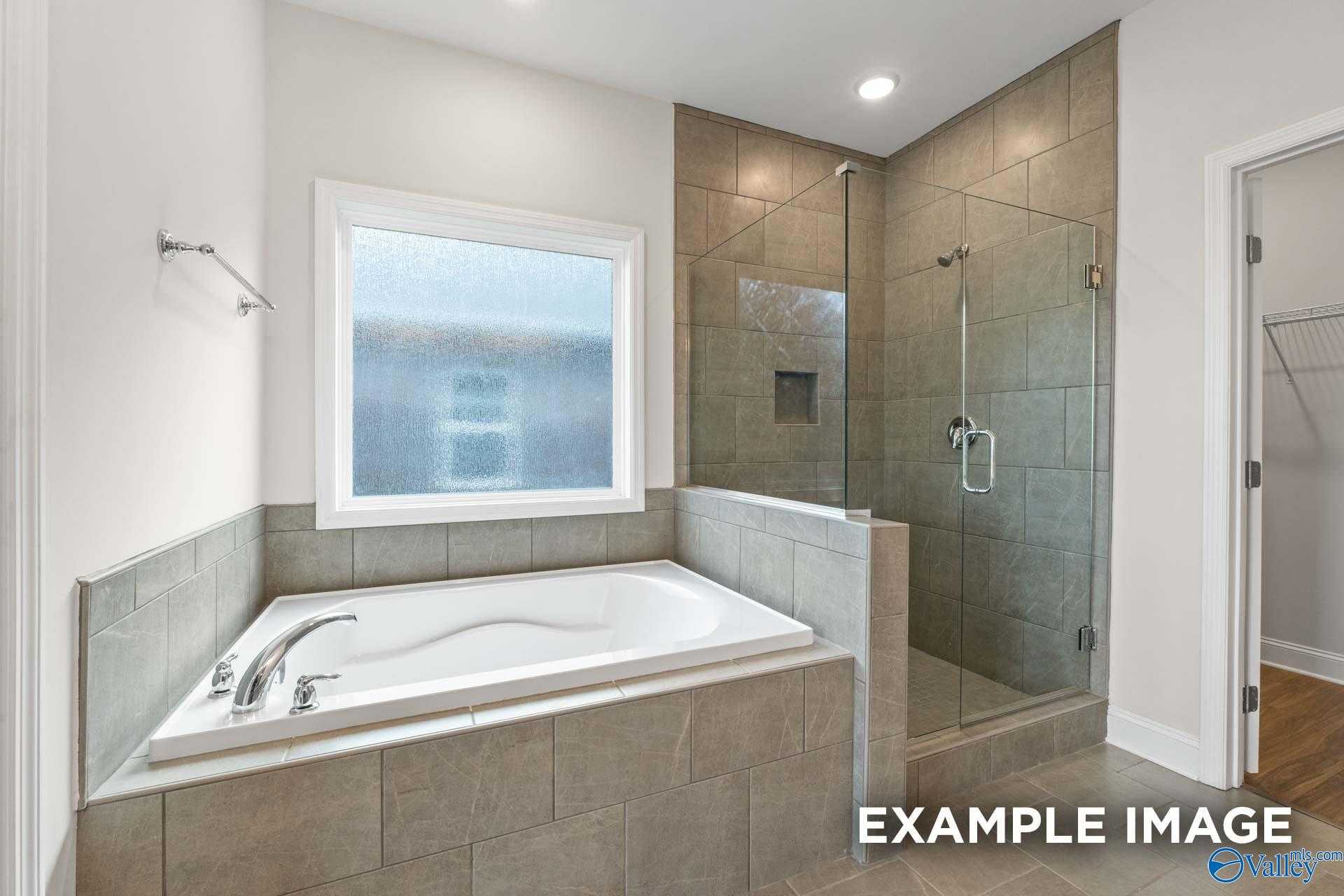 Elegant master bathroom featuring soaking tub, frameless glass shower, and subway tile in Davidson Homes The Montgomery, Athens, Alabama