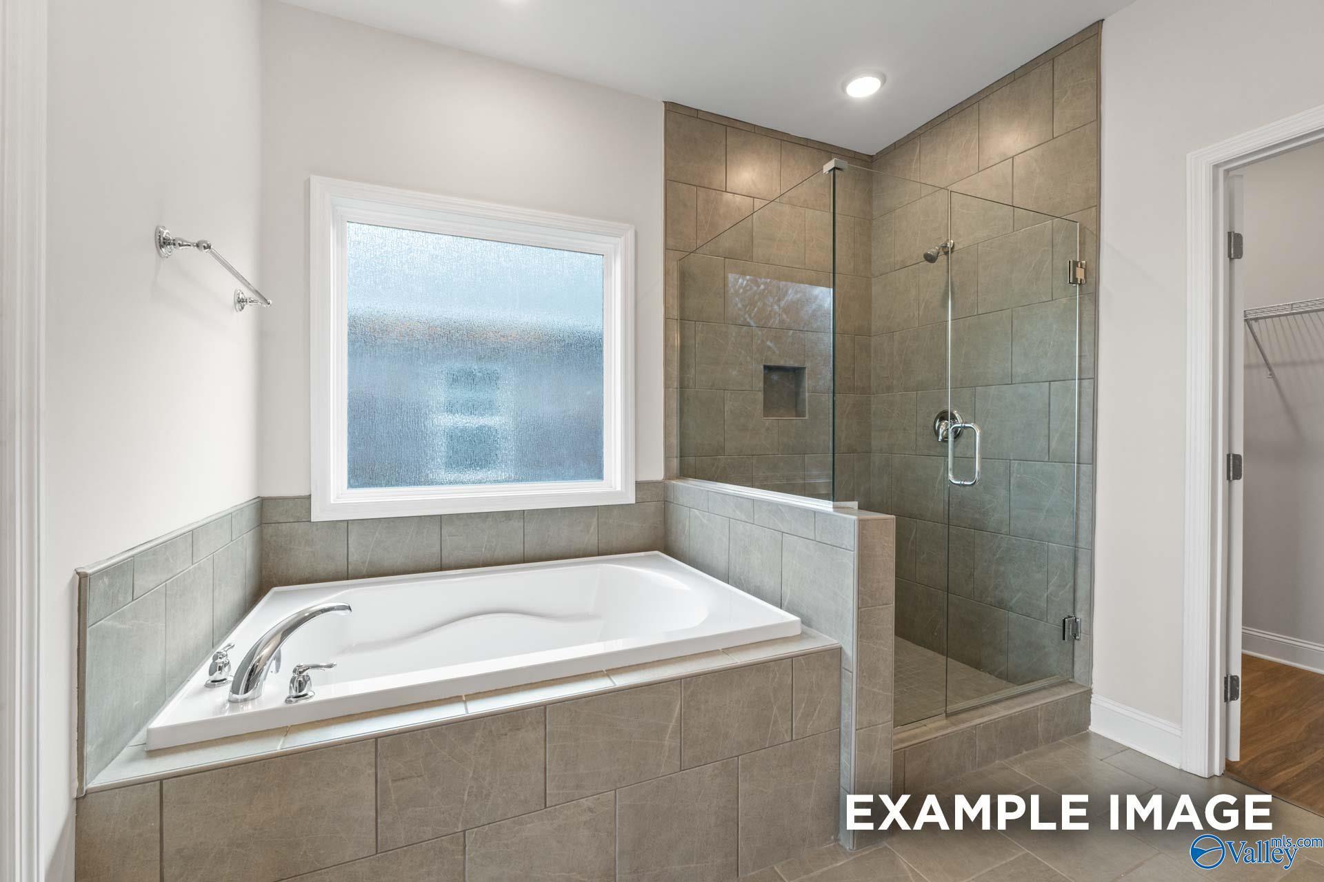 Modern master bathroom featuring freestanding tub, glass shower, and tiled accents in Davidson Homes The Montgomery, Hartselle, AL