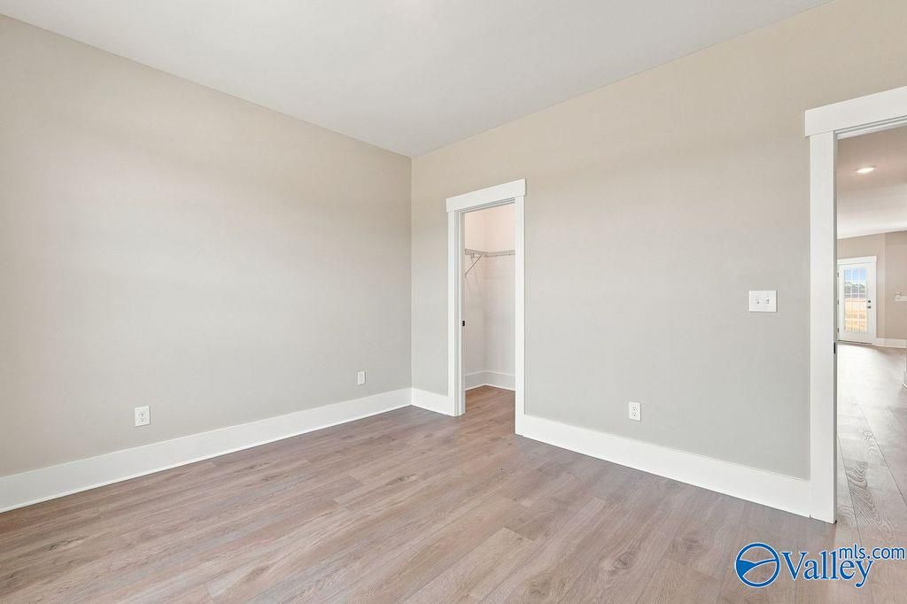 Bright bedroom with wood-look flooring and walk-in closet in The Rockford floor plan by Davidson Homes in Hartselle, AL.