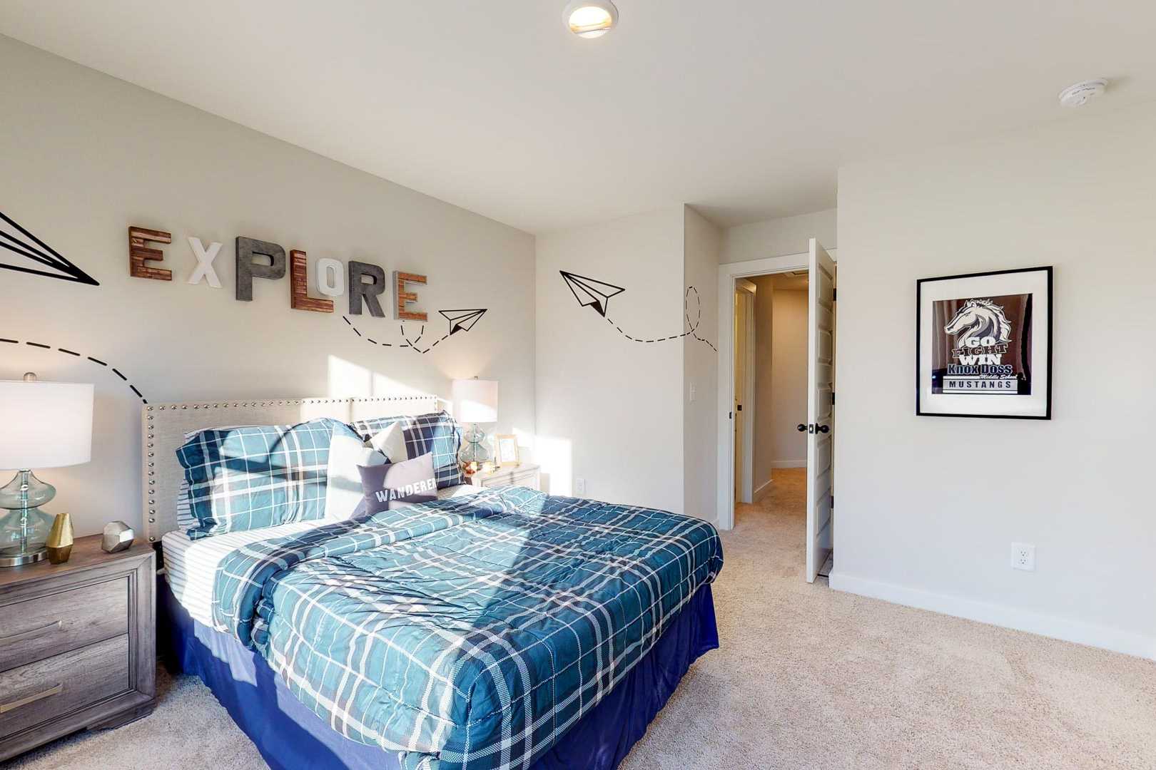 Adventure-themed child's bedroom in Liberty Creek, Gallatin TN with blue plaid bed, paper airplanes, EXPLORE wall letters