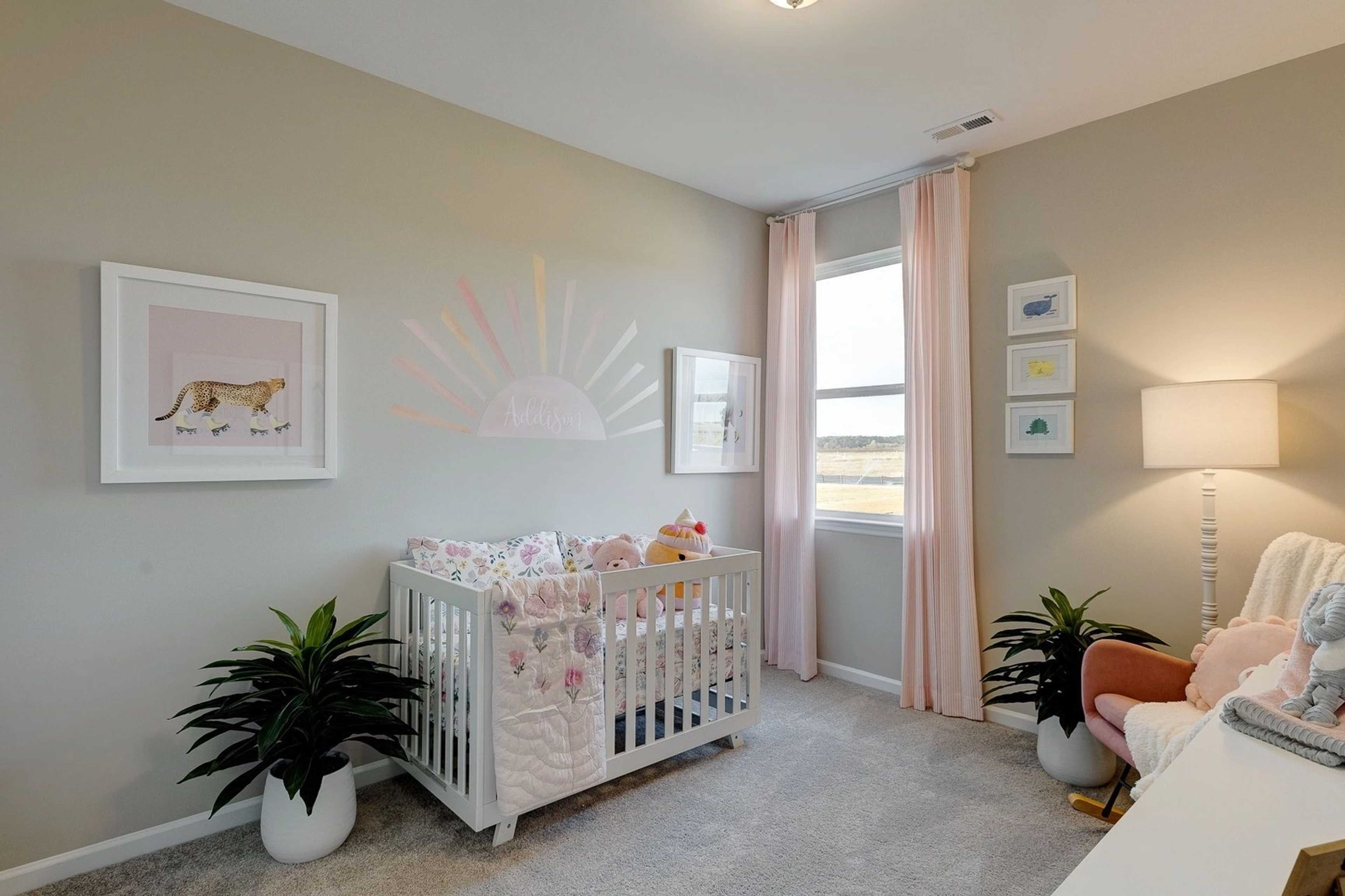 Charming nursery in Carroll Green Harvest AL with white crib pink floral bedding rainbow art and potted plants