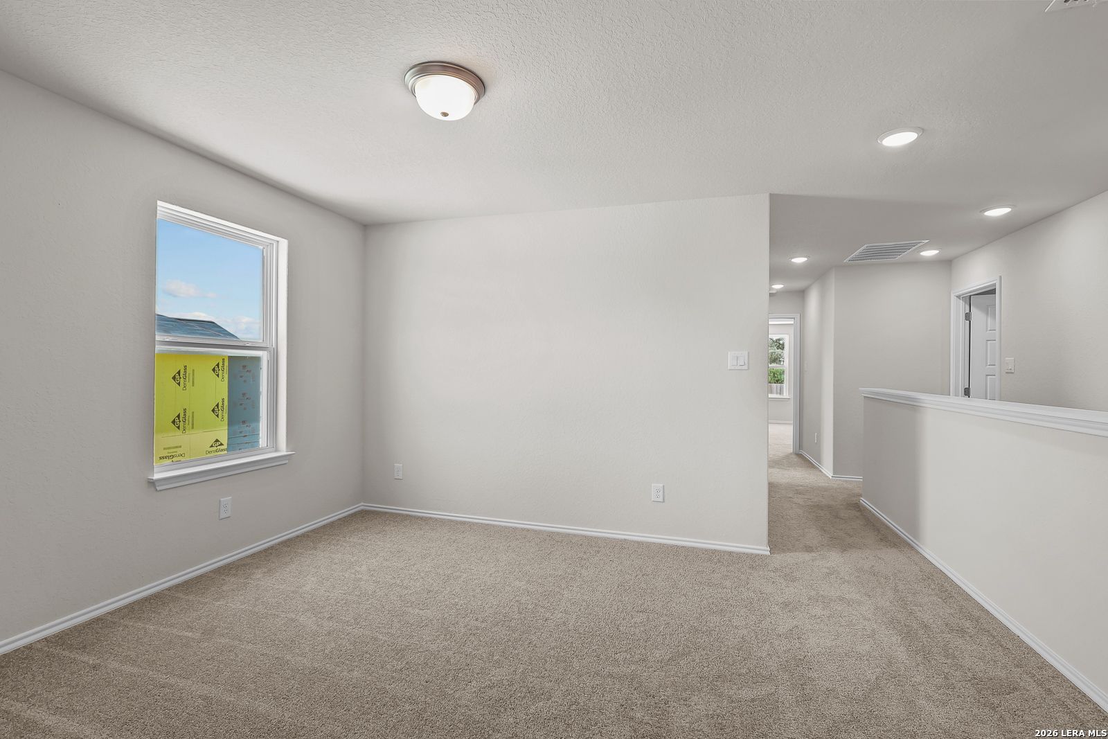 Bright carpeted upstairs loft or secondary bedroom in The Gillian B floor plan at Meadows at Oak Creek, San Antonio.