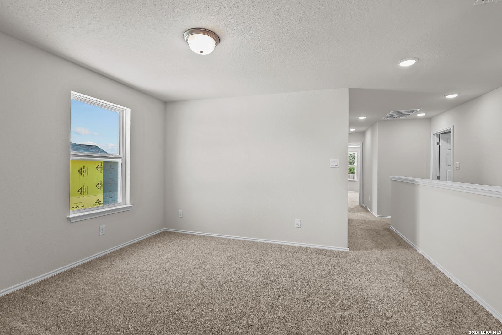 Bright carpeted upstairs loft or secondary bedroom in The Gillian B floor plan at Meadows at Oak Creek, San Antonio.