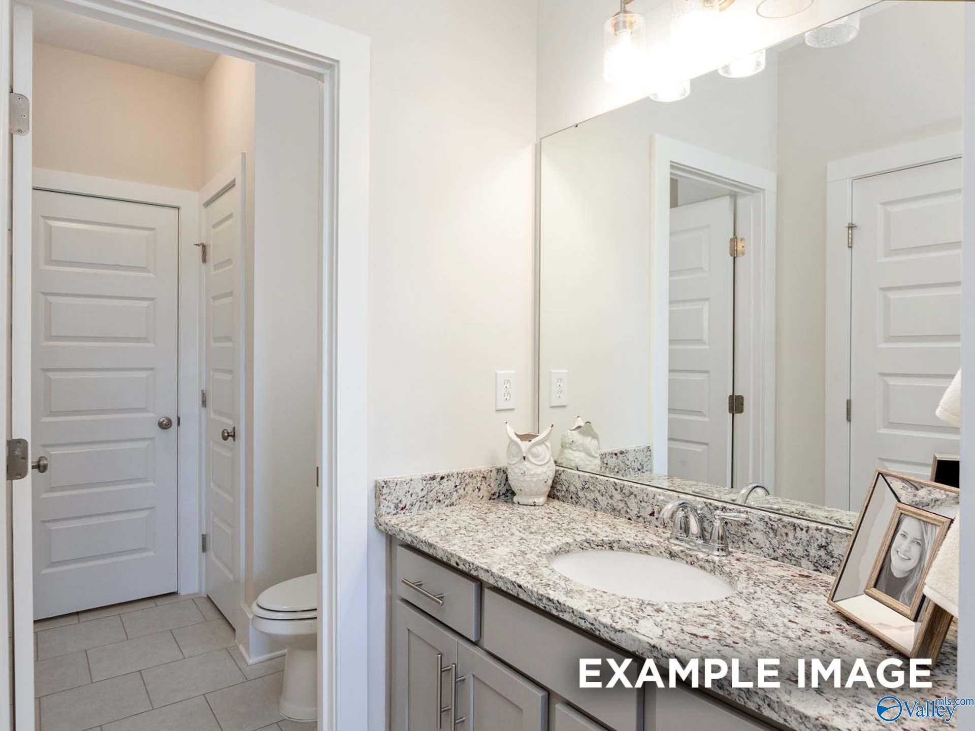 Modern powder room with granite vanity, undermount sink, and large mirror in Davidson Homes The Finleigh, Meridianville, Alabama