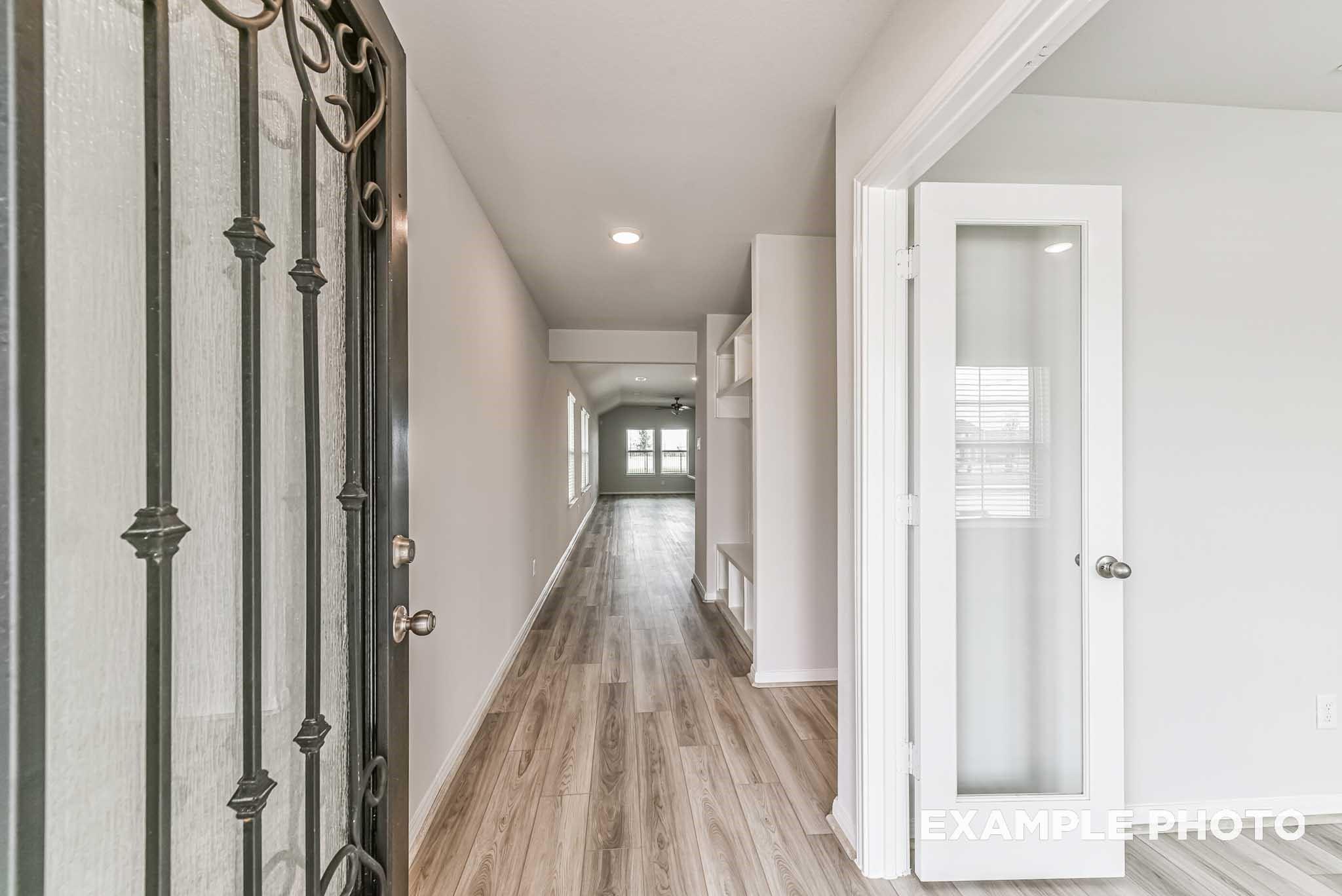 Elegant entry foyer with ornate wrought iron door, light oak hardwood floors, and glass French doors in Davidson Homes Riviera A, Rosharon, Texas