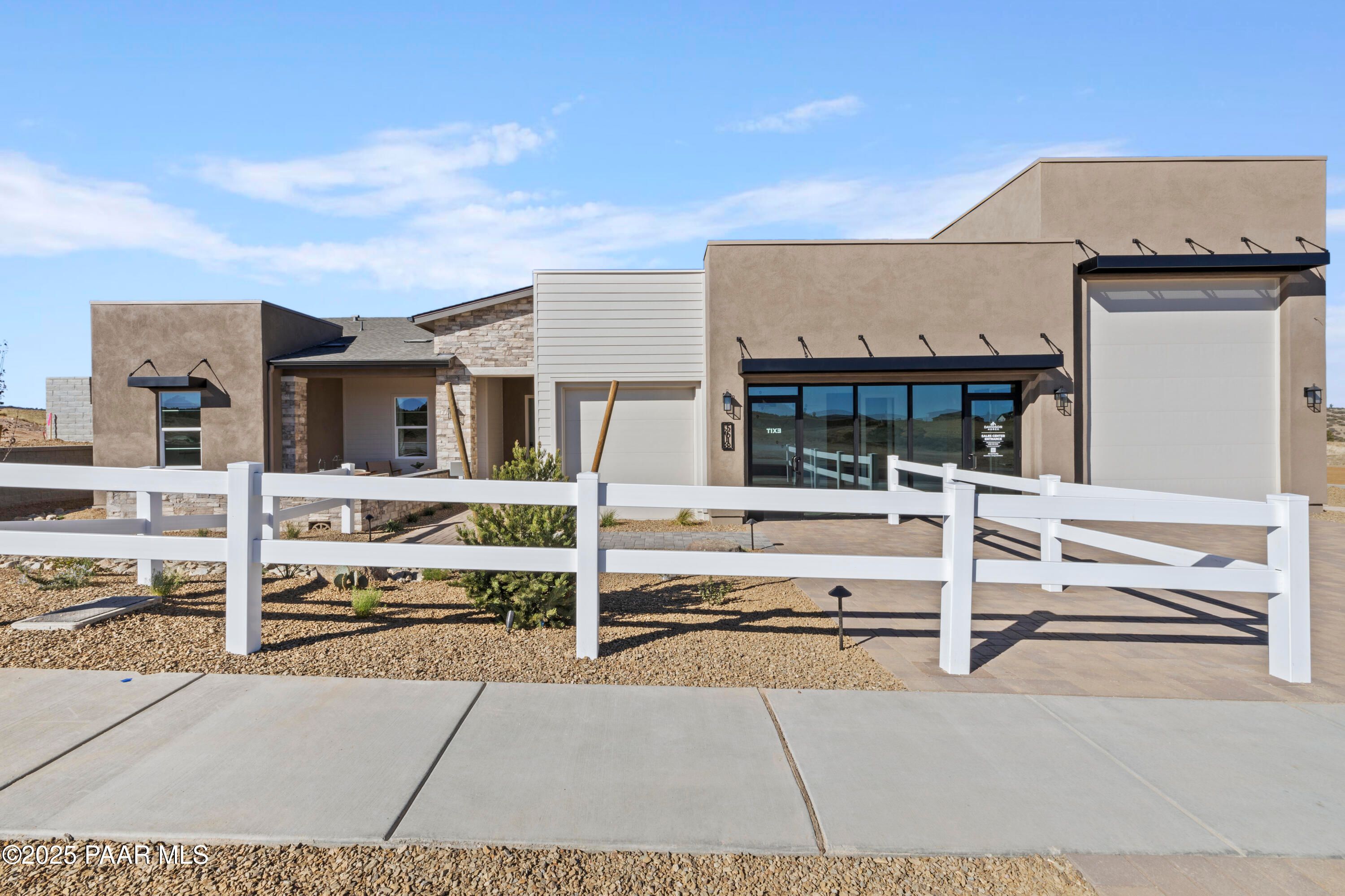 Modern 1-story 3-bedroom home by Davidson Homes, The Blaze D floor plan, with beige stucco exterior, 3-car garage, and white fence in Hidden Hills, Prescott, AZ