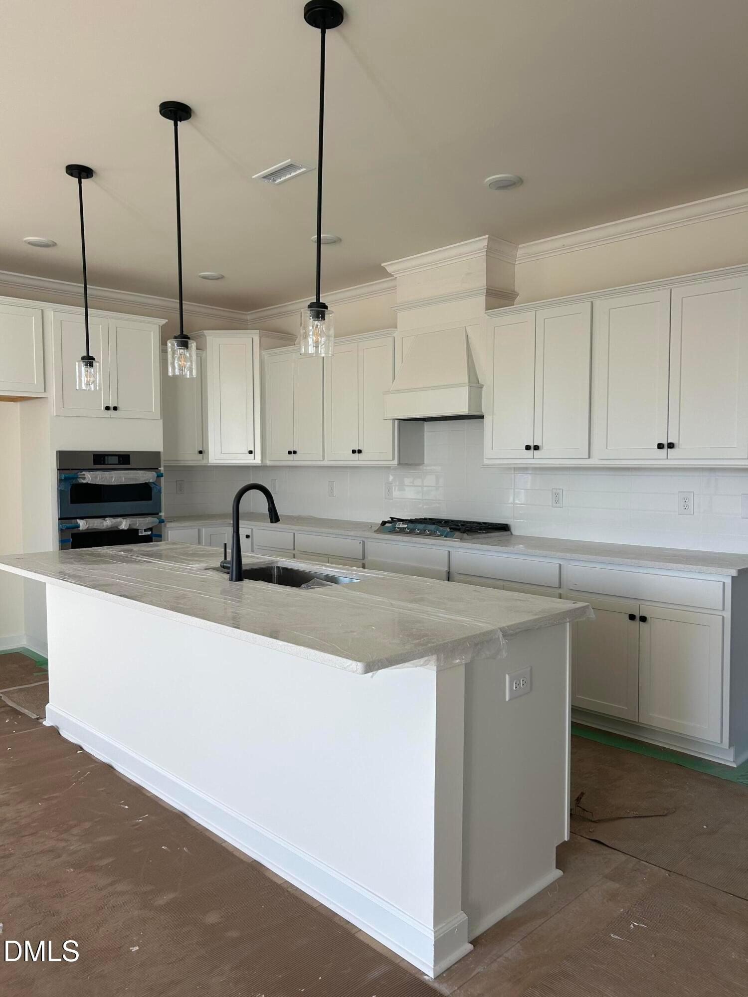 Modern white kitchen featuring quartz island, stainless steel oven, gas cooktop, and pendant lights in Davidson Homes Magnolia B, Angier, NC