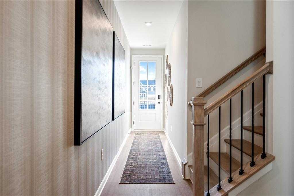 Elegant hallway with abstract wall art, glass-paneled front door, and oak staircase in Davidson Homes The Marion C, Winder, Georgia