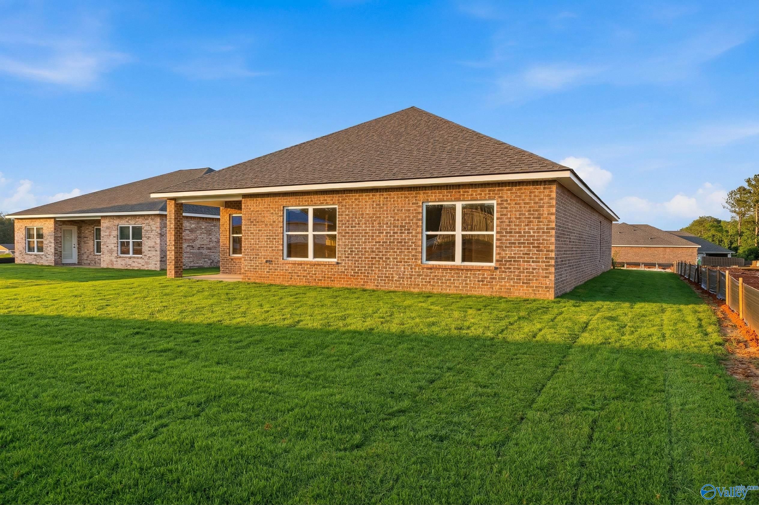 Single-story brick home with gabled roof, covered porch, and large windows on lush green lawn in Blue Spring, Huntsville, Alabama