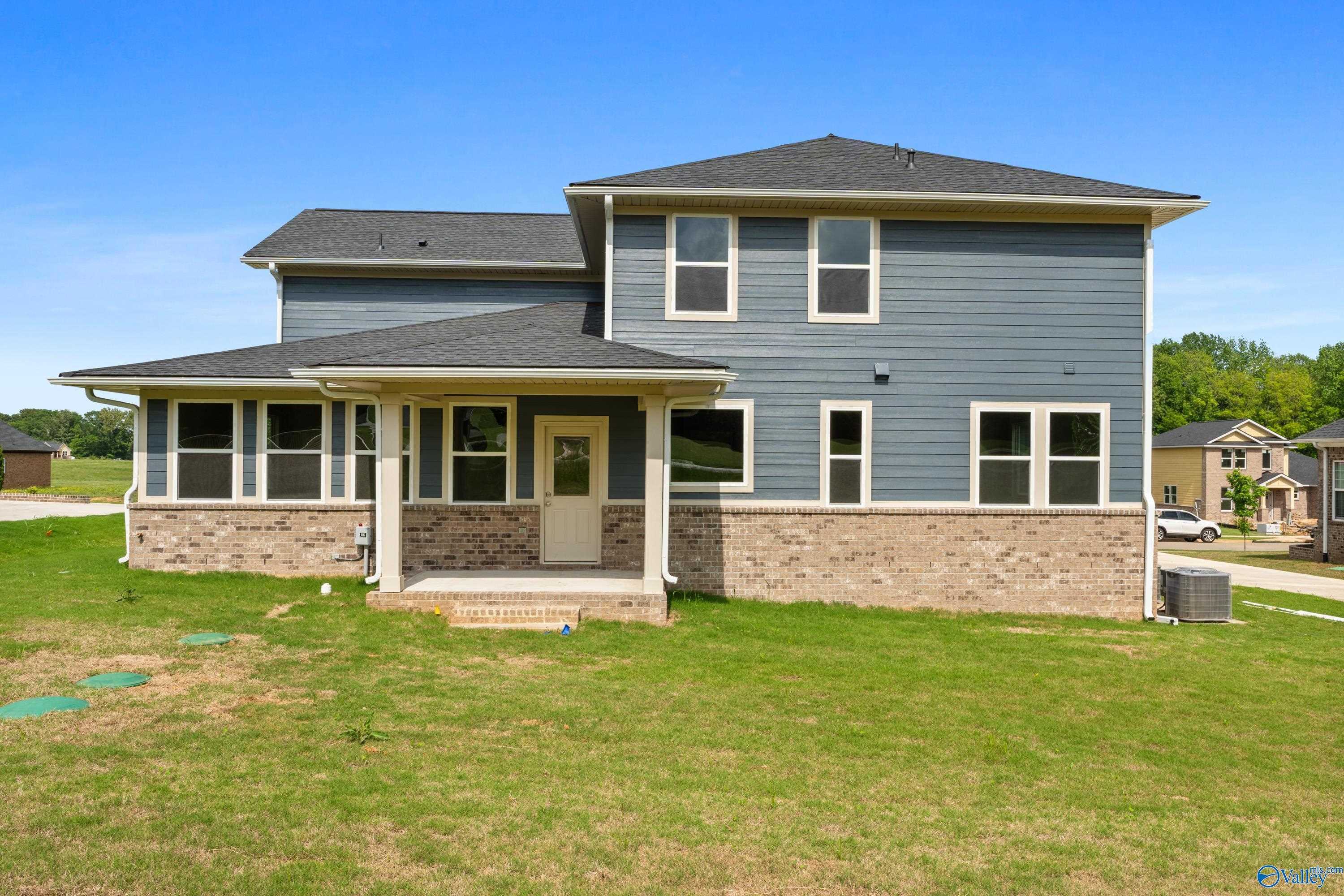 Two-story blue-sided home with brick accents, covered porch, and large windows in Riverton Preserve, Huntsville, Alabama