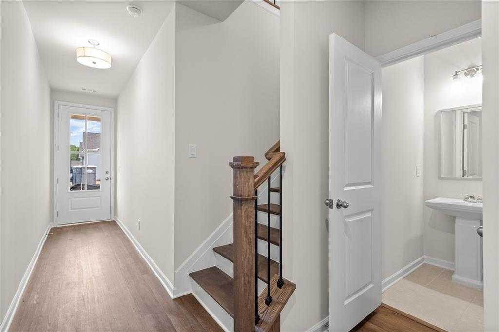 Bright foyer hallway with wood floors, oak staircase, and powder room in Davidson Homes The Marion B, Kennesaw, Georgia