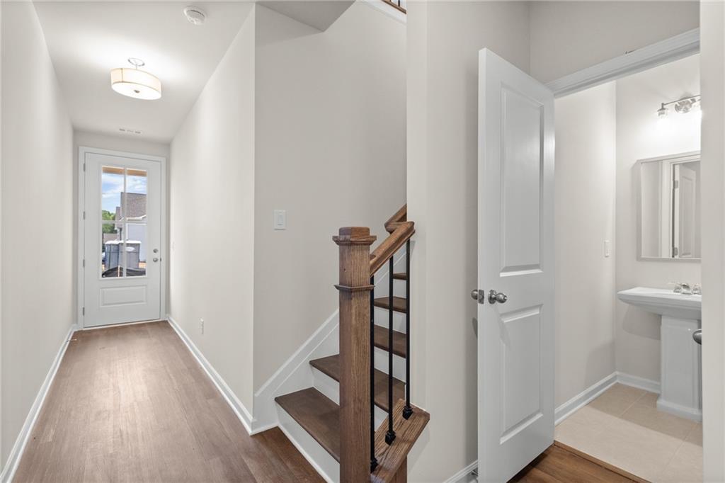Bright entry hallway with hardwood floors, wooden staircase, and powder room in The Marion B by Davidson Homes, Kennesaw, Georgia