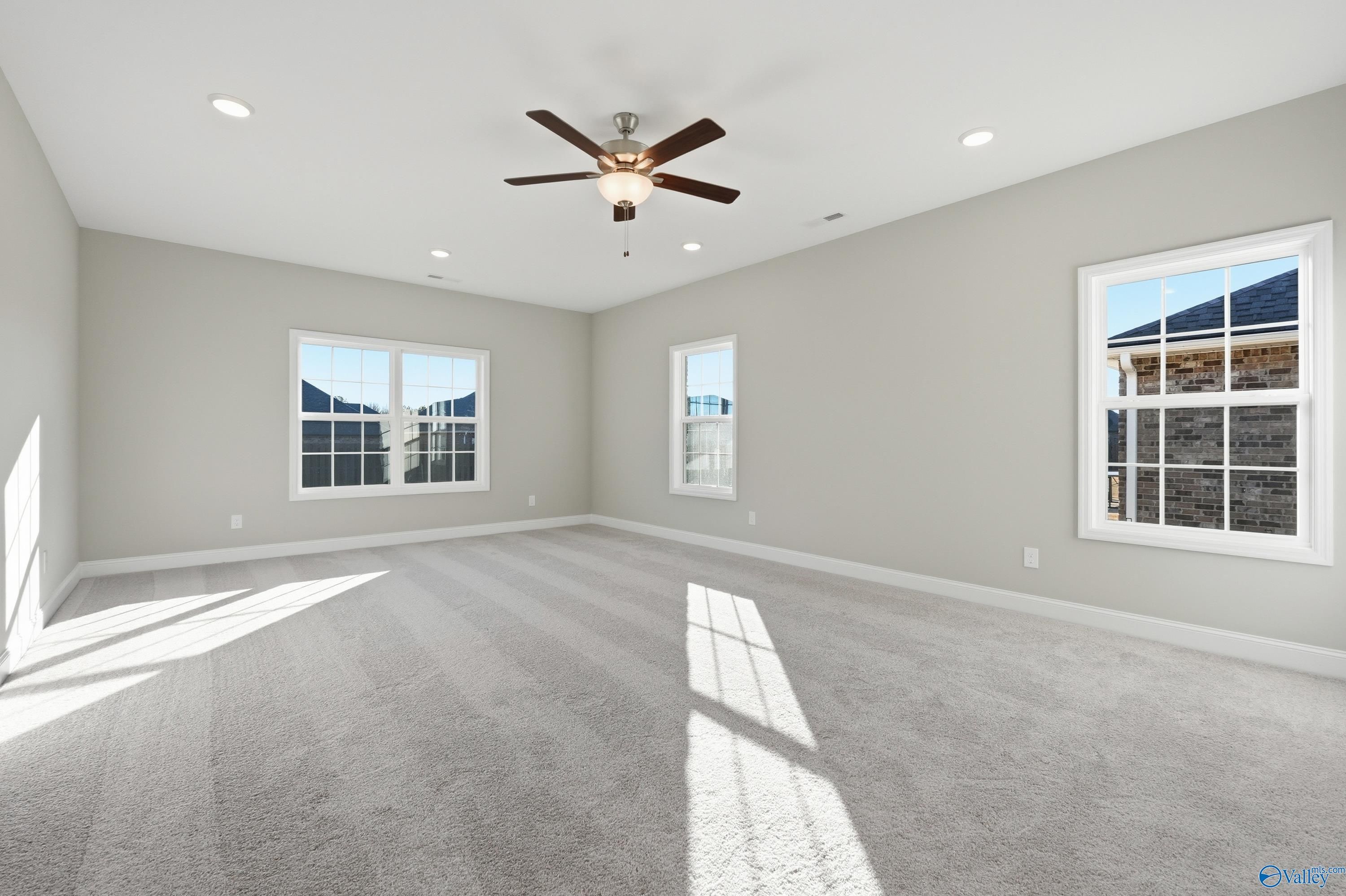 Bright secondary bedroom with gray walls, large windows, ceiling fan, and carpeted floor in Davidson Homes The Lanier, Toney, Alabama