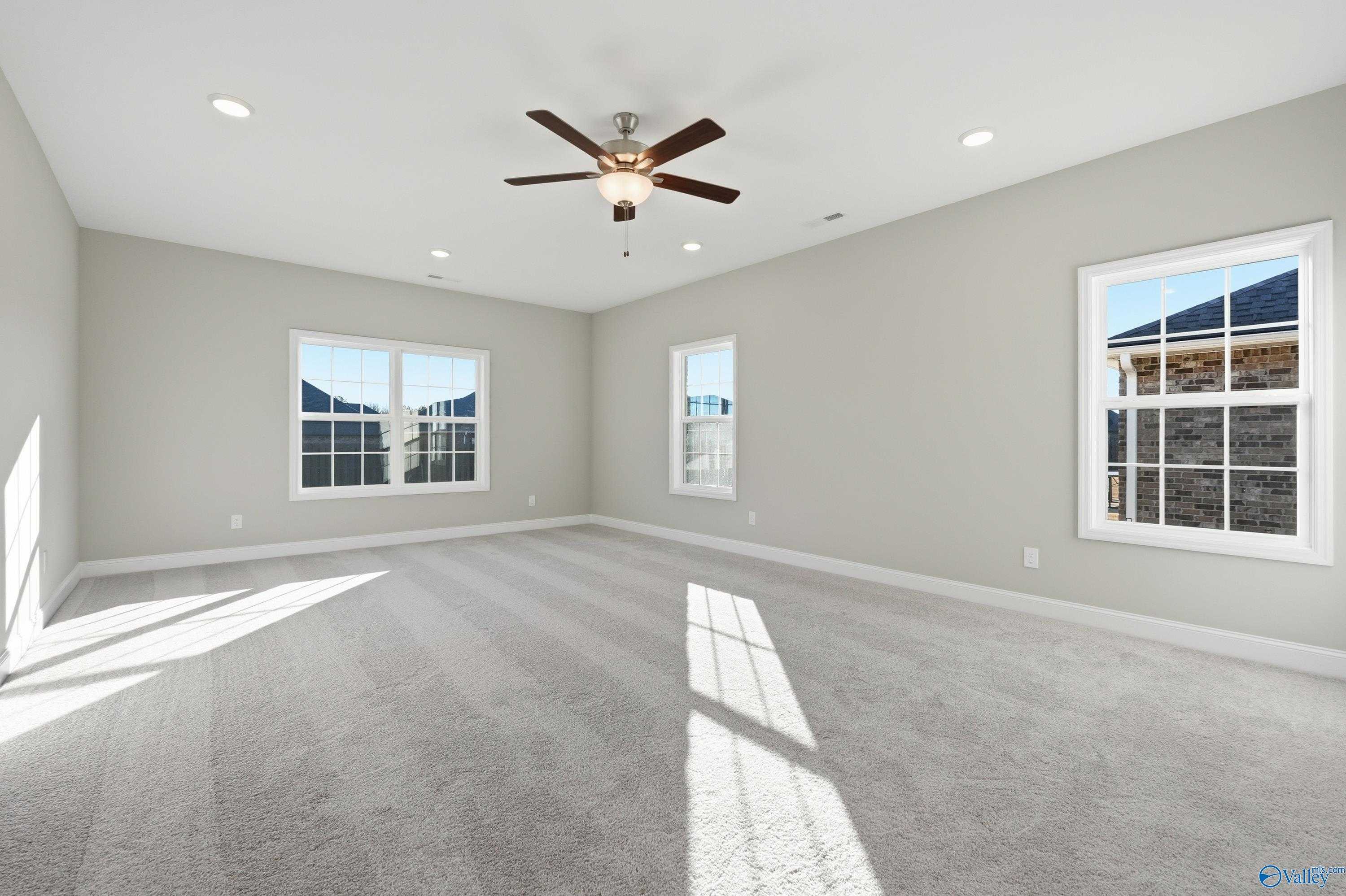 Bright secondary bedroom with gray walls, large windows, ceiling fan, and carpeted floor in Davidson Homes The Lanier, Toney, Alabama