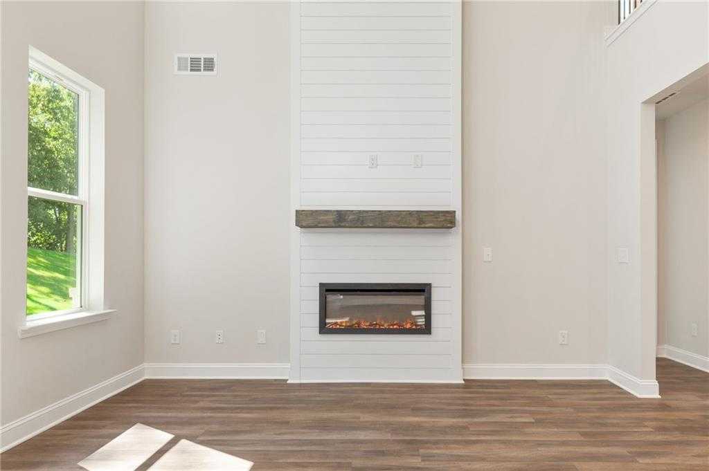 Shiplap gas fireplace with flames and wooden mantel in open family room of 5-bedroom Danbury E home, Buford, Georgia