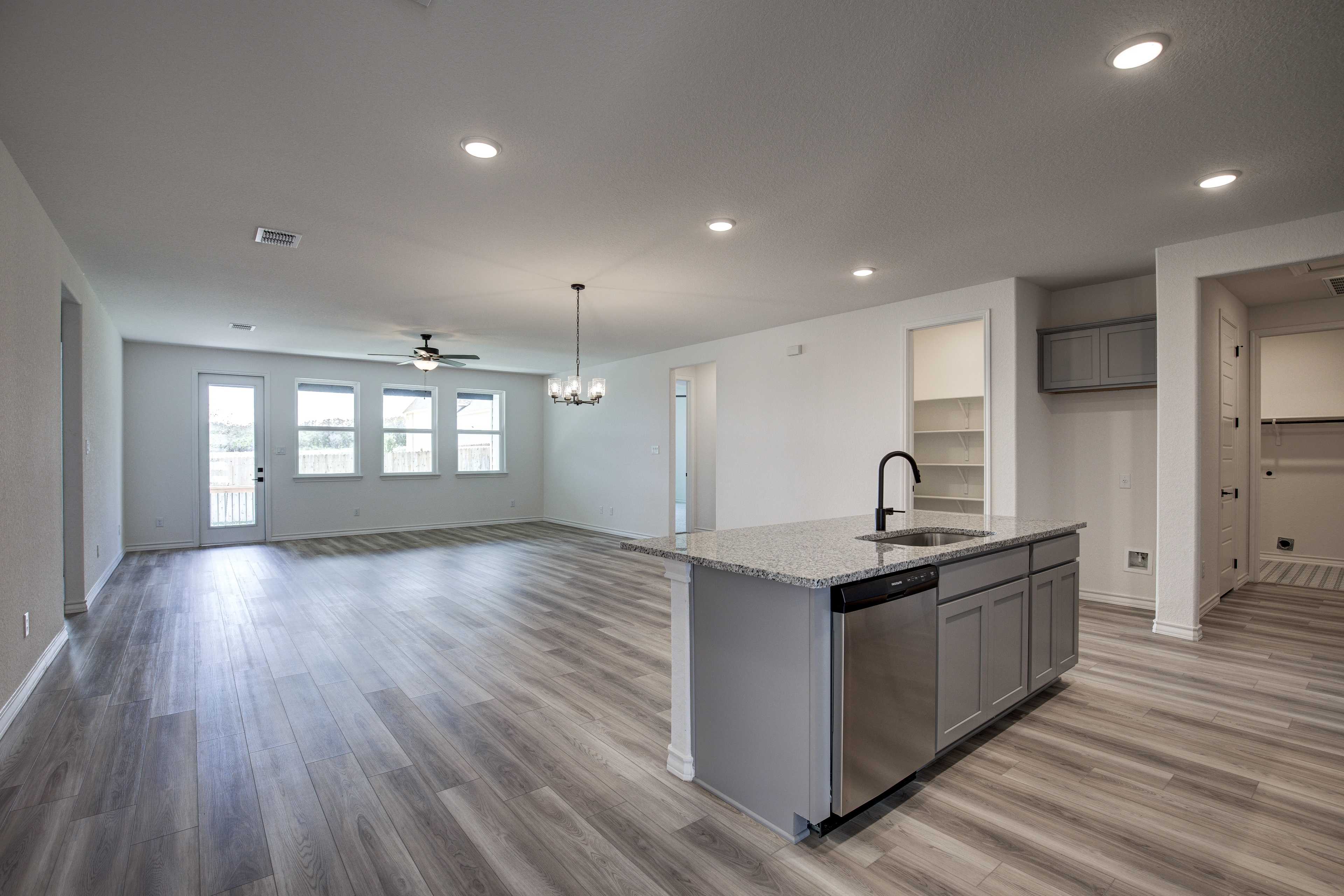 Spacious open-concept kitchen and living area in The Lanier home with gray island, stainless dishwasher, hardwood floors, and large windows