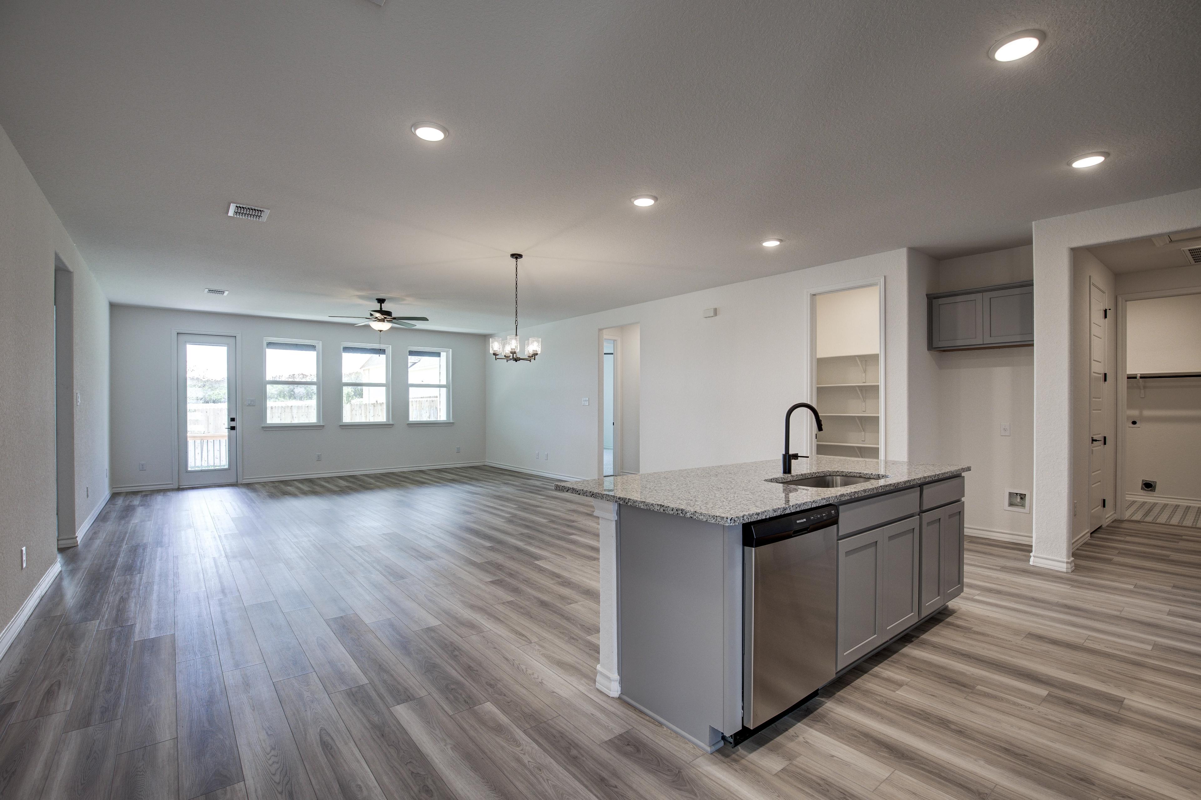 Spacious open-concept kitchen and living area in The Lanier floor plan by Davidson Homes, with large gray island, hardwood floors, and recessed lighting