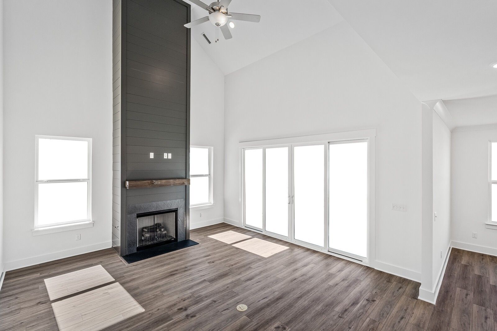 Vaulted great room with tall stone fireplace, ceiling fan, hardwood floors, and French doors in Davidson Homes The Hawkins, Murfreesboro, TN