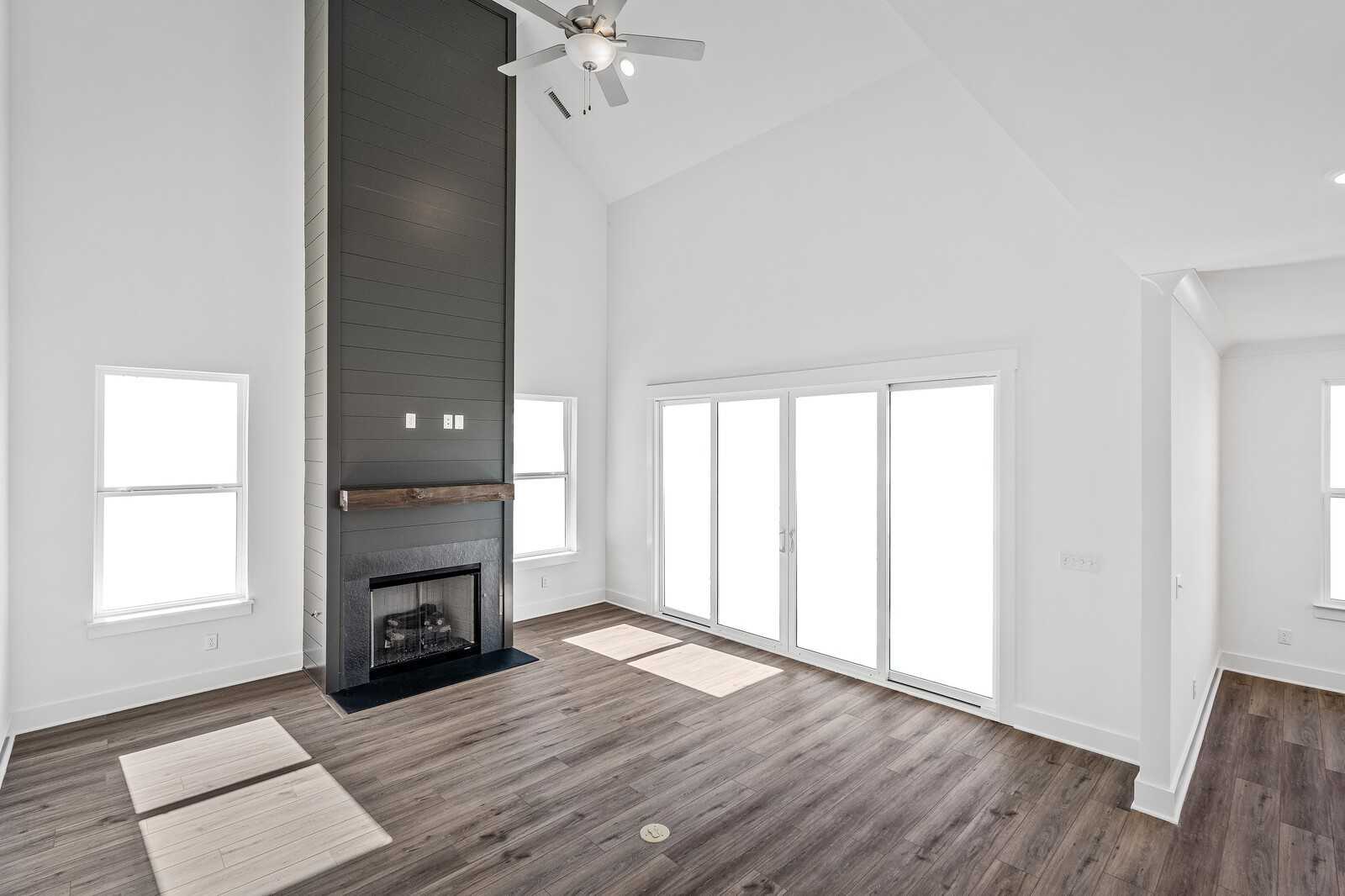 Vaulted great room with tall stone fireplace, ceiling fan, hardwood floors, and French doors in Davidson Homes The Hawkins, Murfreesboro, TN