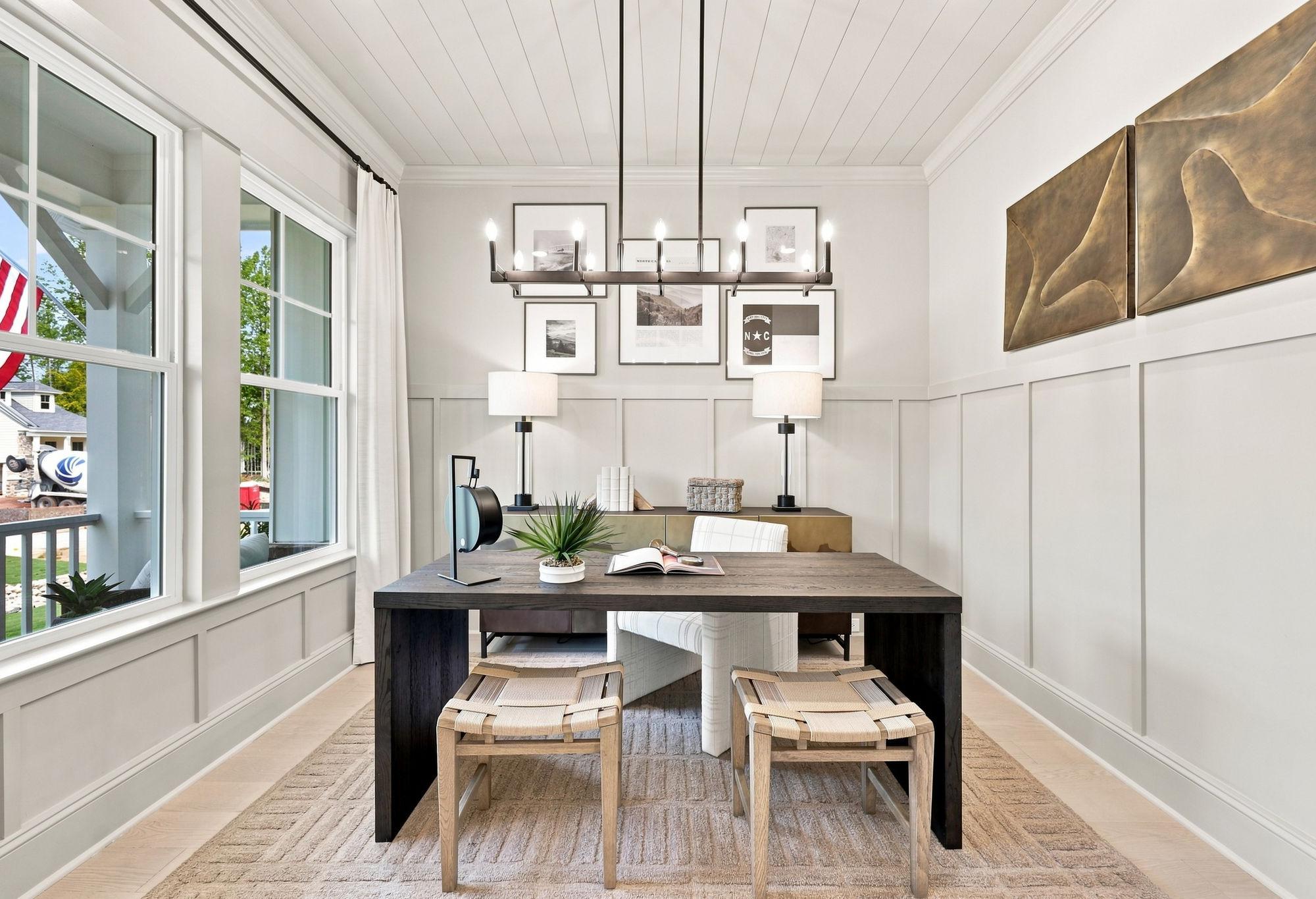 Modern home office in The Barrington featuring board and batten walls, a dark wood desk, and stylish lighting.