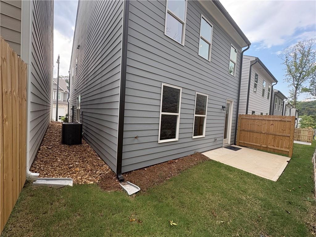 Side view of modern gray two-story Davidson Homes Cary A with wooden privacy fence, AC unit, and landscaped yard in Kennesaw, Georgia