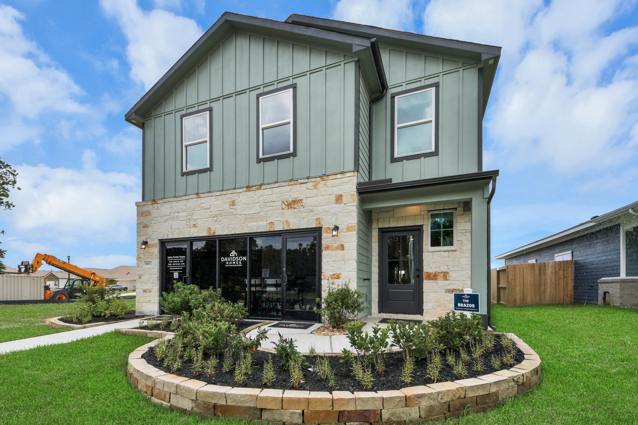 Davidson Homes model home exterior at Robins Landing in Houston, Texas featuring stone accents and modern green siding.