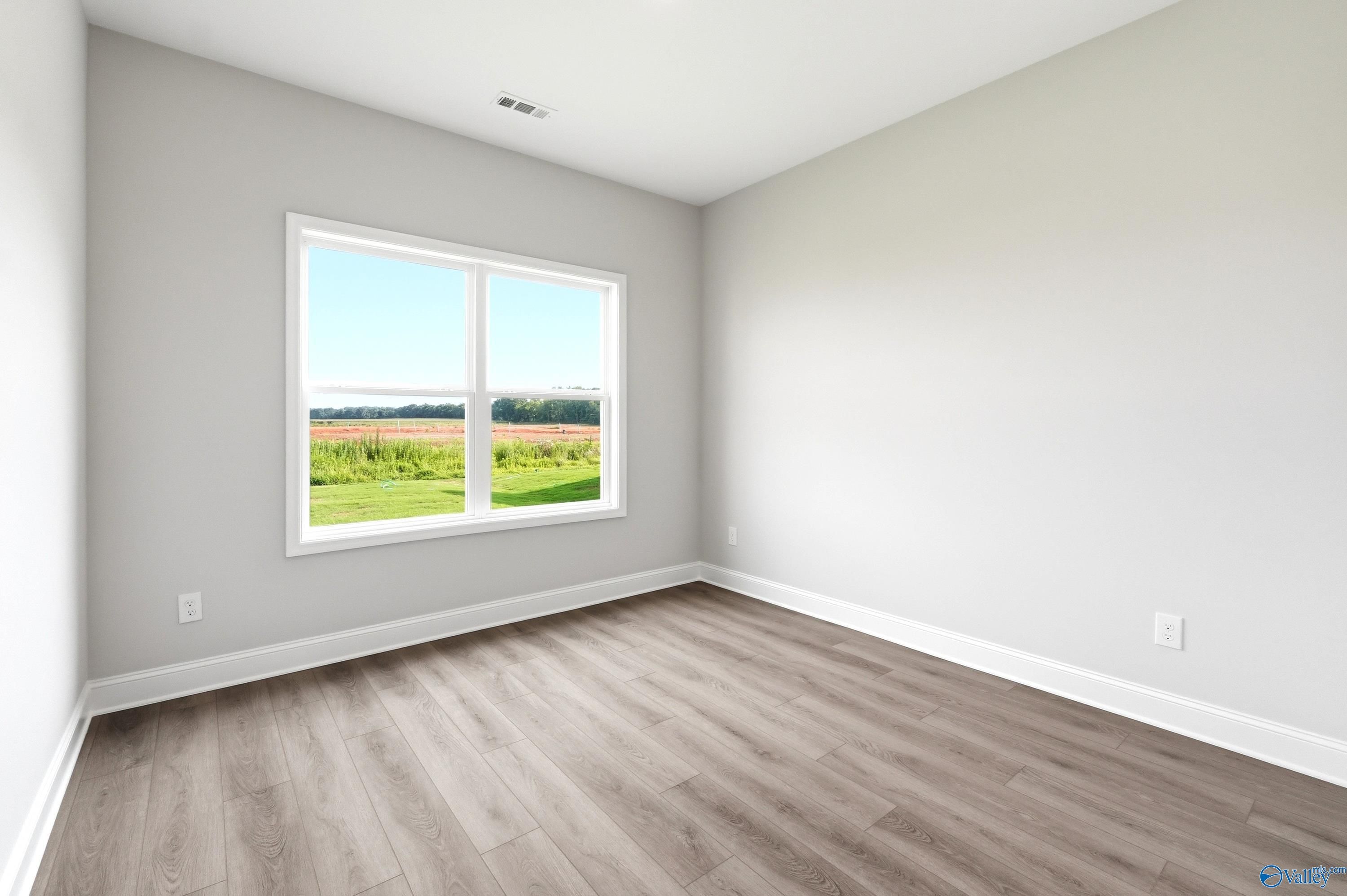 Bright bedroom with gray walls and wood-look flooring in The Shelby A floor plan at Clearview, Hazel Green, Alabama.