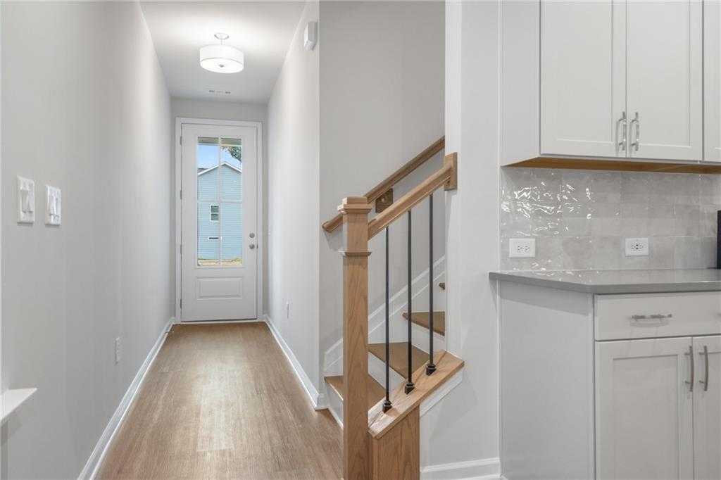 Bright entry hallway with oak staircase and white cabinet kitchen in Davidson Homes The Cary A, Kennesaw, Georgia