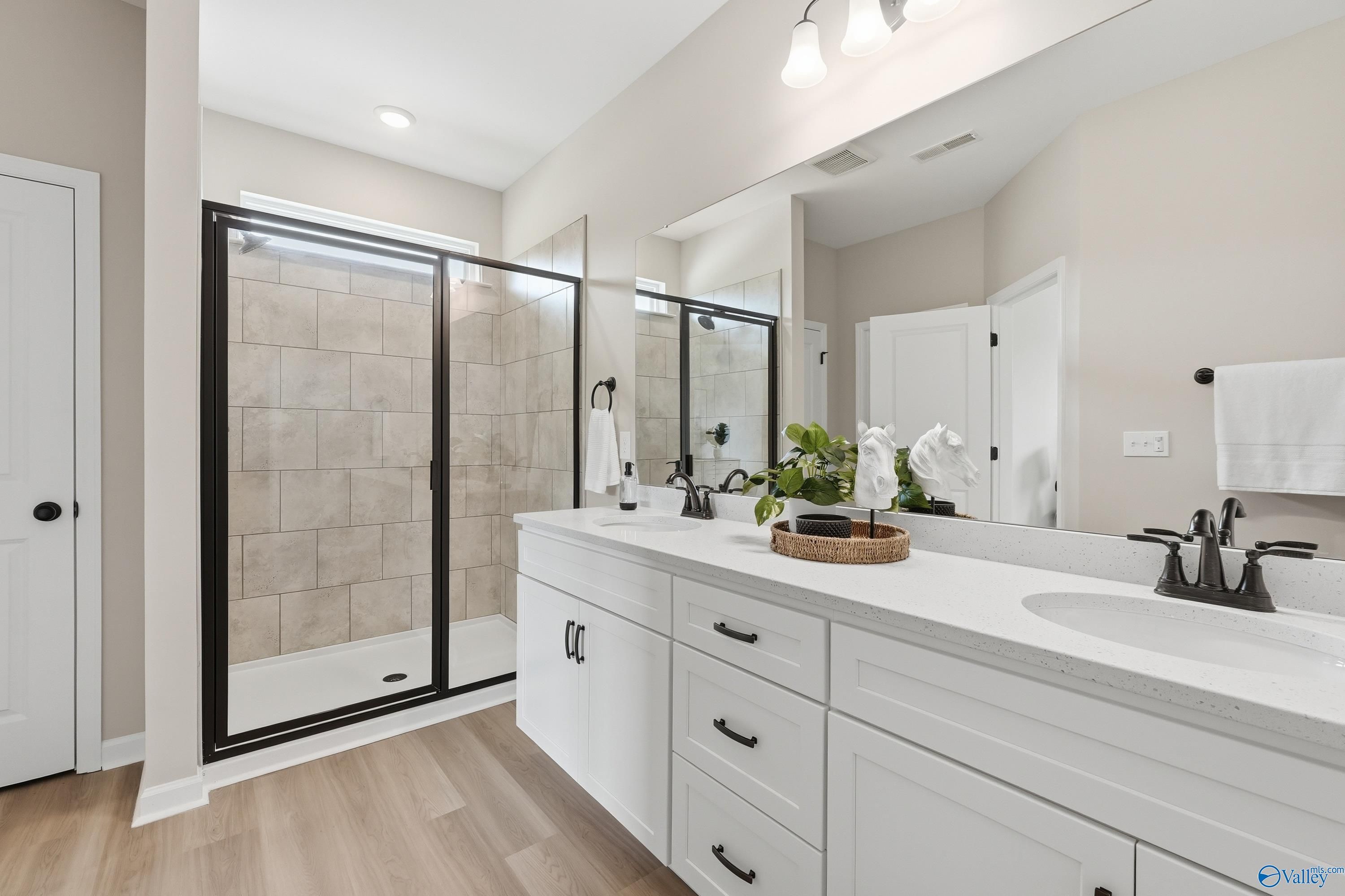 Modern master bathroom featuring frameless glass shower, beige tile, white double vanity, quartz counters in Davidson Homes The Dorado, Huntsville AL