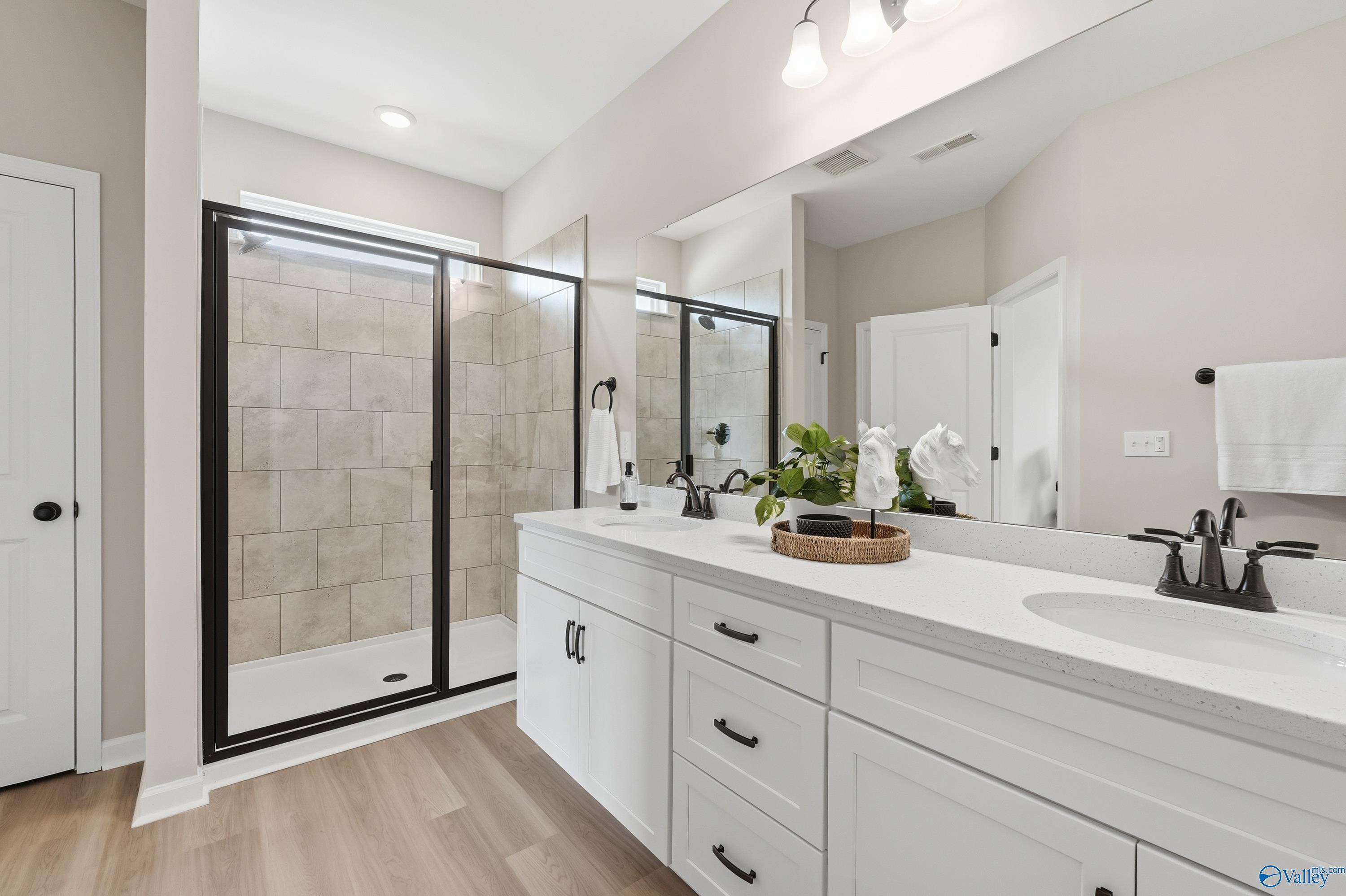 Modern master bathroom featuring frameless glass shower, beige tile, white double vanity, quartz counters in Davidson Homes The Dorado, Huntsville AL