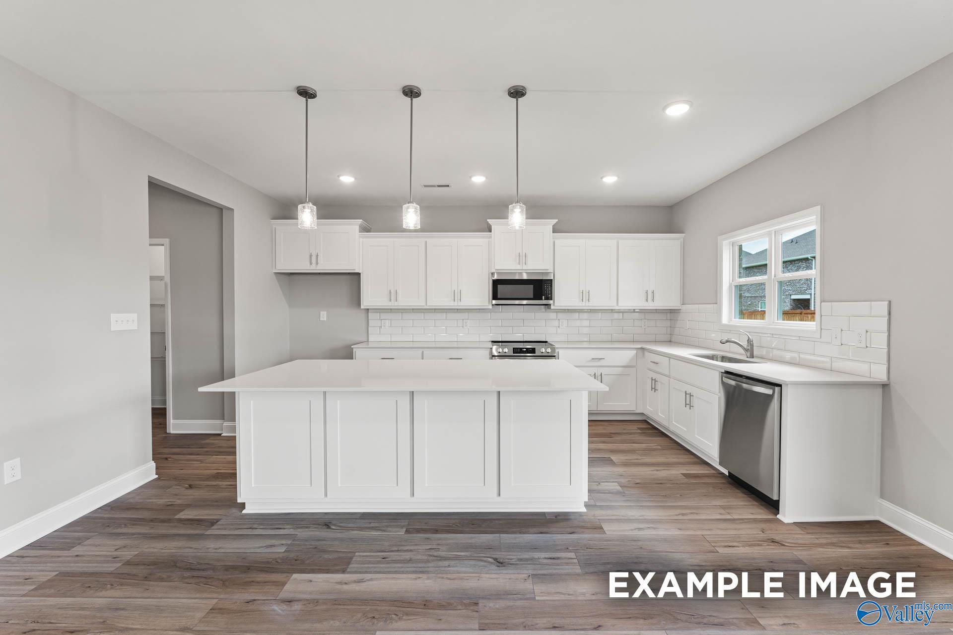 Modern white kitchen with large island, stainless steel appliances, subway tile backsplash in Davidson Homes Chelsea B, Toney AL