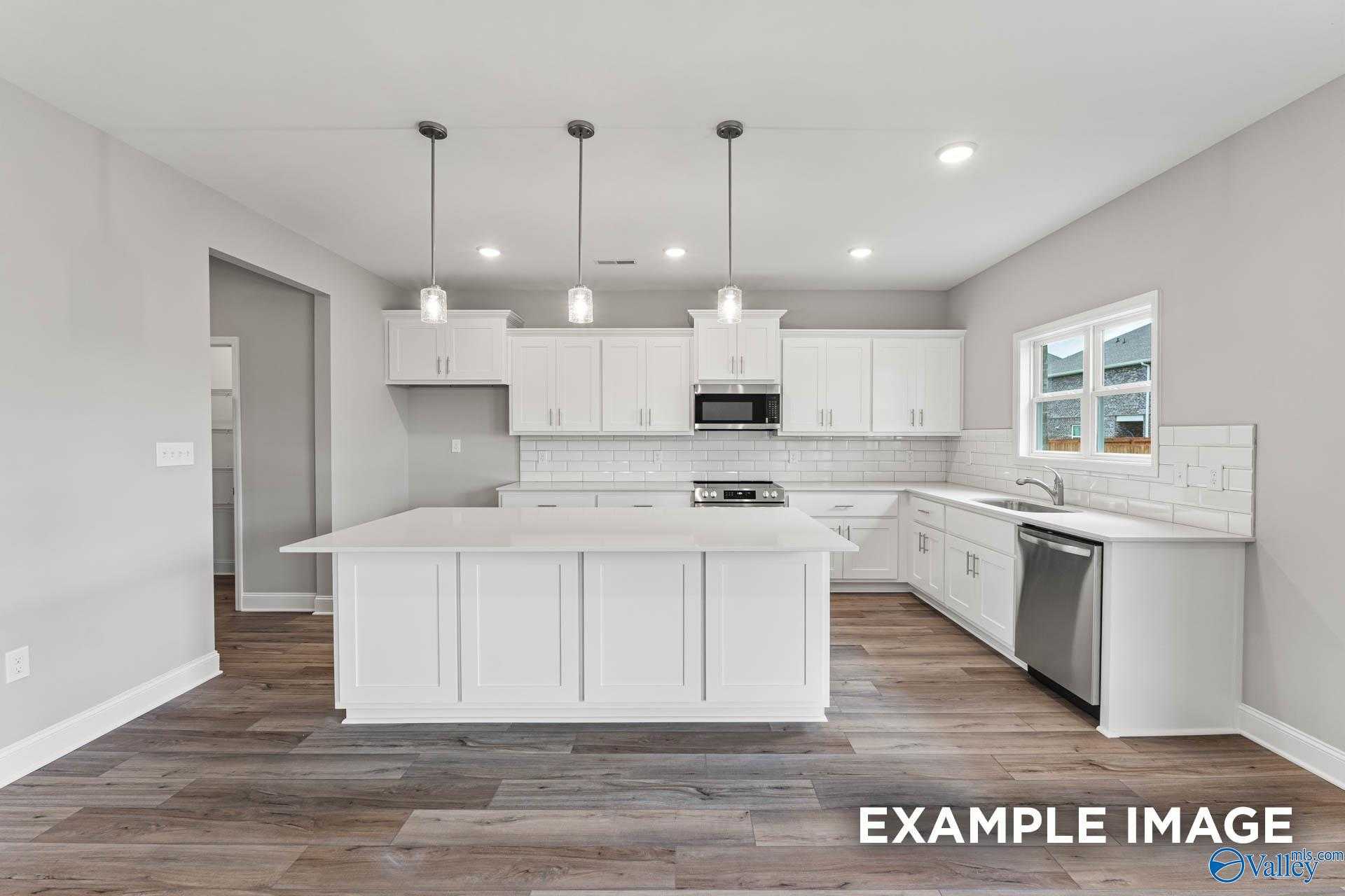 Open-concept kitchen with white shaker cabinets, large island, stainless appliances in Davidson Homes Chelsea A, Athens AL