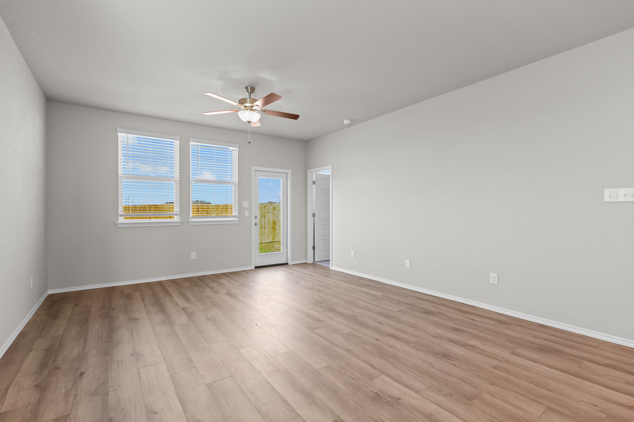 Spacious, light-filled living area in The Colorado B floor plan featuring wood-look flooring and backyard access.