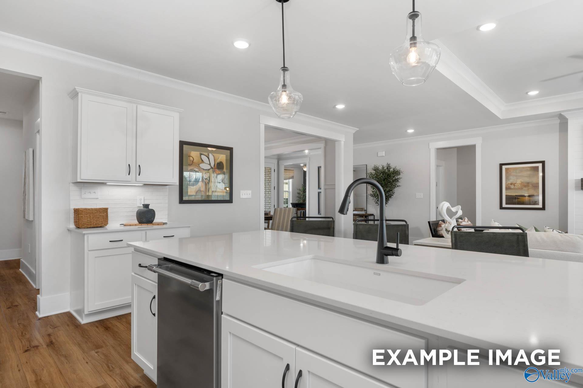 Modern white shaker kitchen with quartz island, farmhouse sink, and open living room in The Finleigh home, Decatur AL