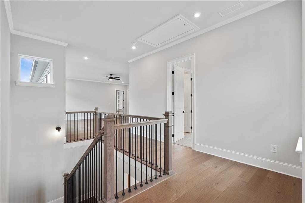 Elegant oak staircase with black iron balusters and ceiling fan in 2-story The Seaside B home, Woodstock, Georgia