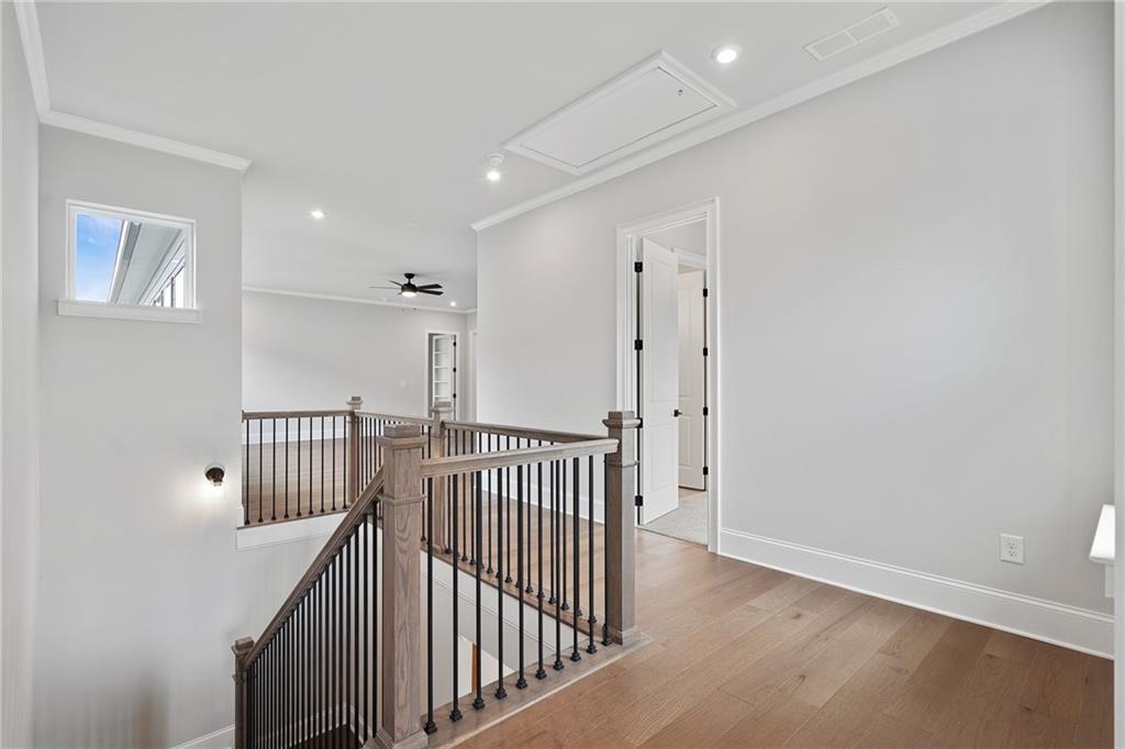 Elegant oak staircase with black iron balusters and ceiling fan in 2-story The Seaside B home, Woodstock, Georgia