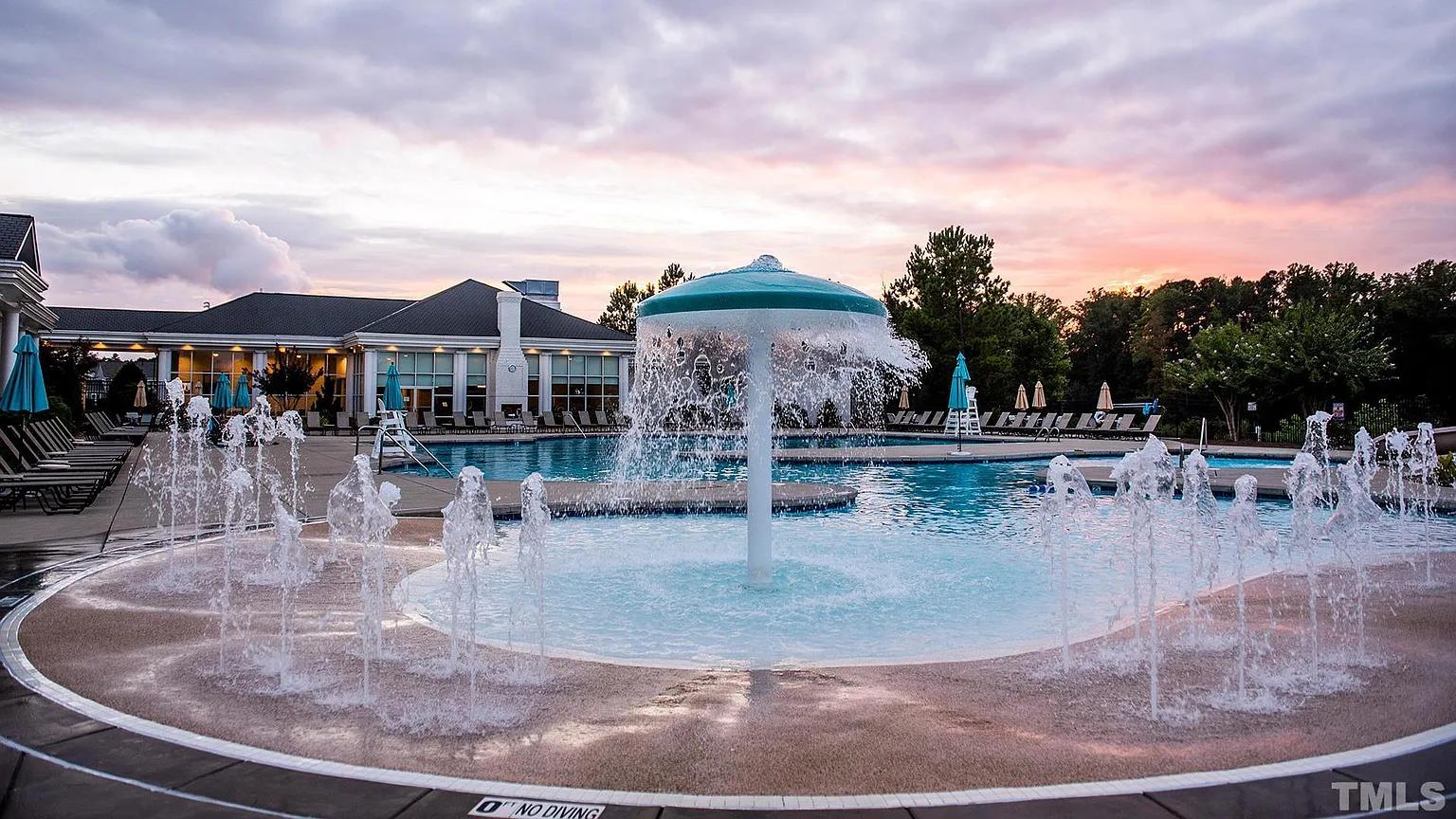 Circular splash pad with spraying water jets and central umbrella fountain at Addison West in Holly Springs NC