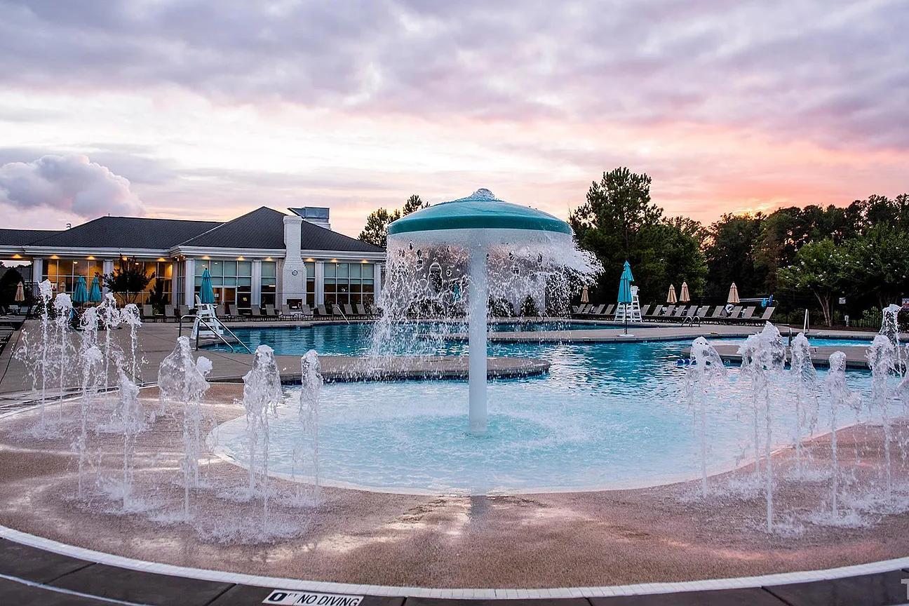 Circular splash pad with spraying water jets and central umbrella fountain at Addison West in Holly Springs NC