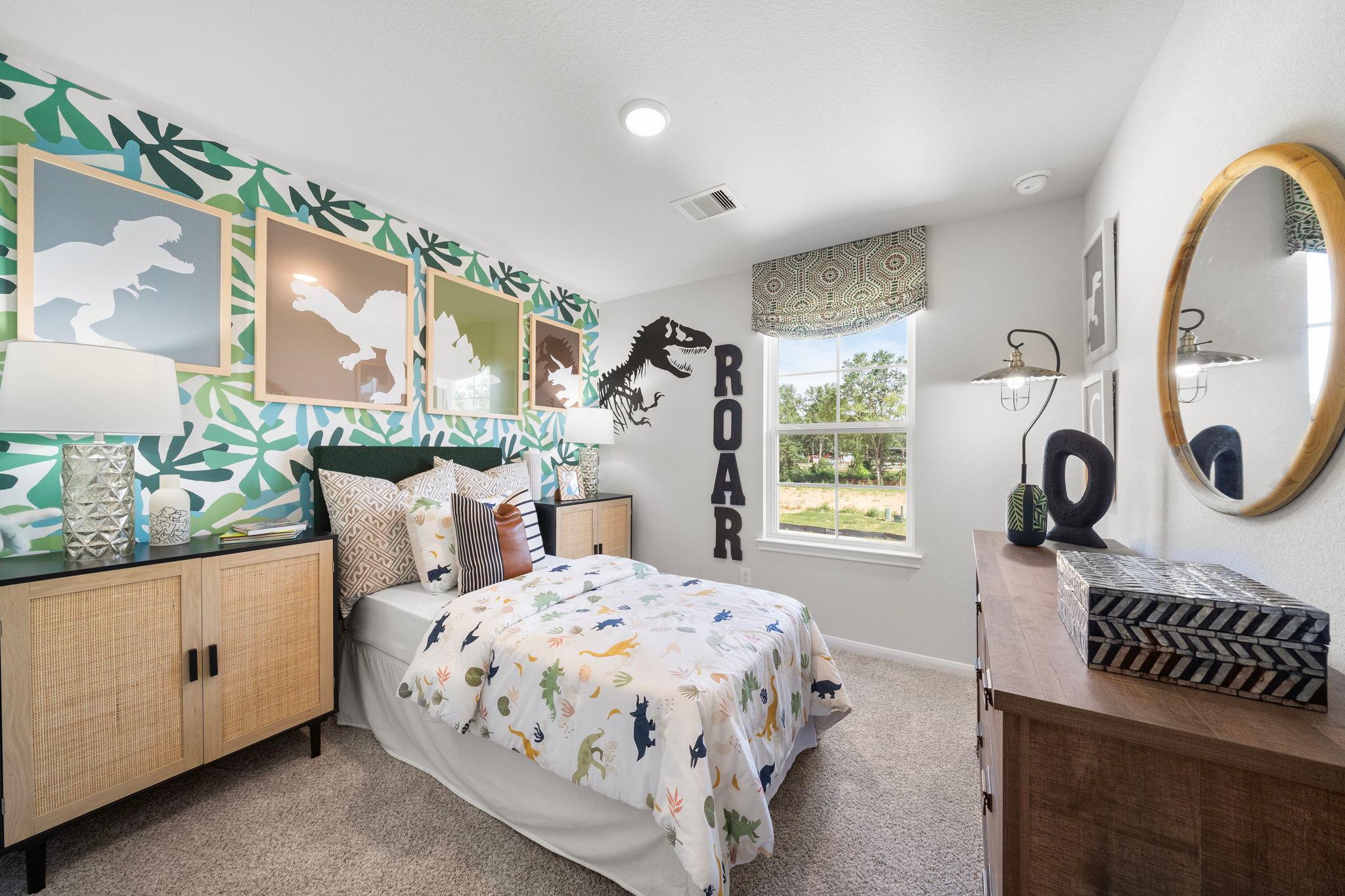 Dinosaur-themed kids bedroom at Caney Creek Place in Conroe TX with leafy green wallpaper, twin bed and ROAR wall sign