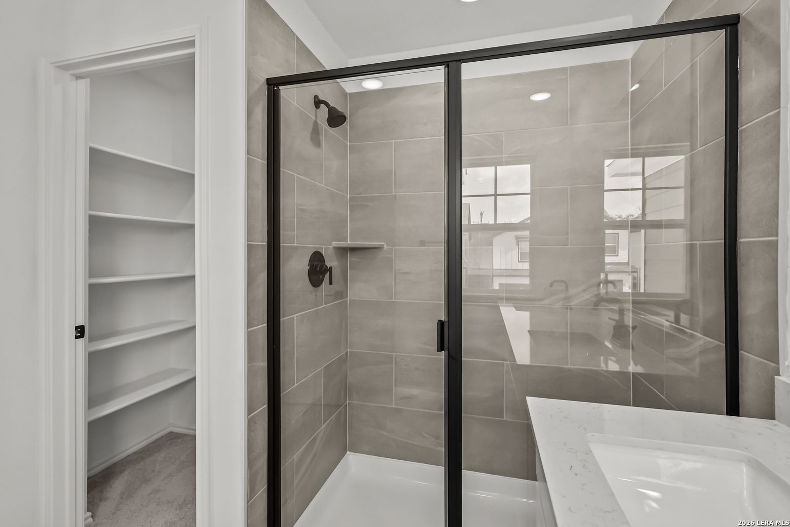 Modern walk-in shower with black frame and tiled walls in The Florence B floor plan, Meadows at Oak Creek, San Antonio.