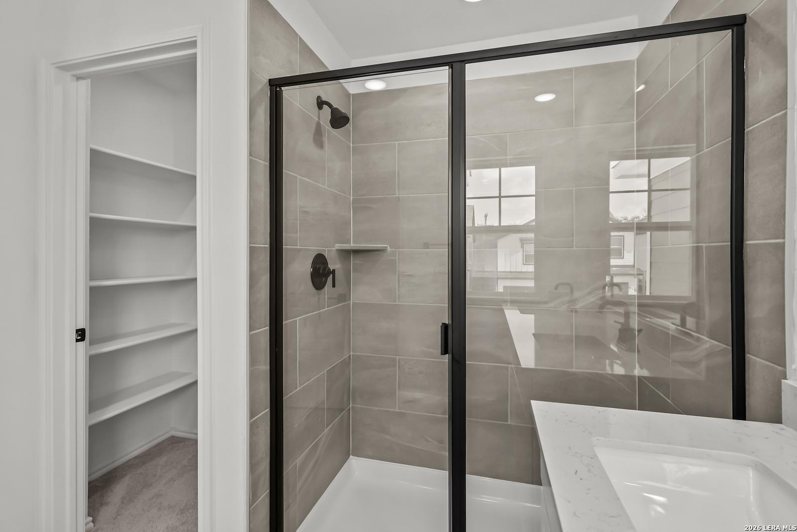 Modern walk-in shower with black frame and tiled walls in The Florence B floor plan, Meadows at Oak Creek, San Antonio.