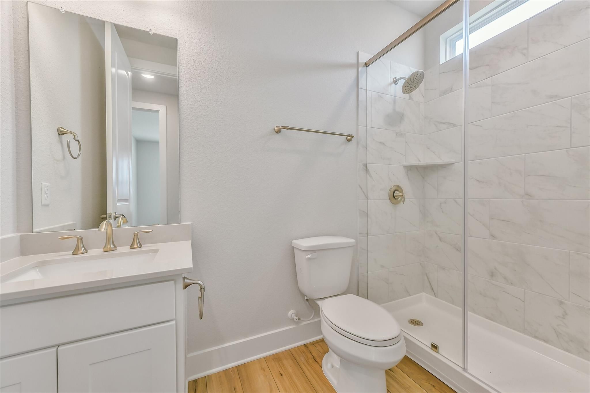 Modern bathroom featuring glass-enclosed marble shower, gold fixtures, white vanity in Davidson Homes The Victoria A, Lago Mar, Texas