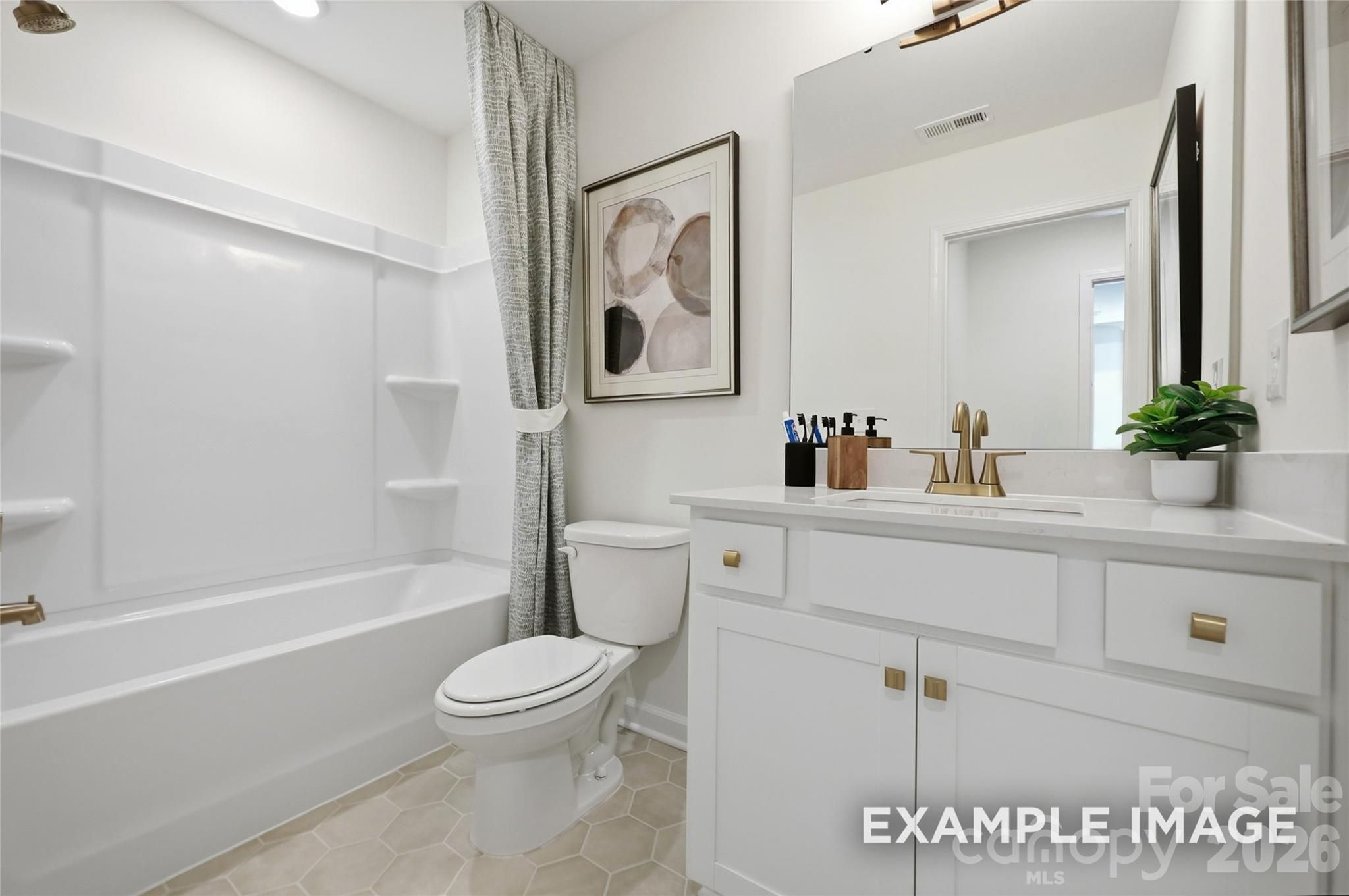 Bright white bathroom with tub, toilet, and vanity with gold fixtures in Davidson Homes The Aspen B, Windgate, Mooresville, NC