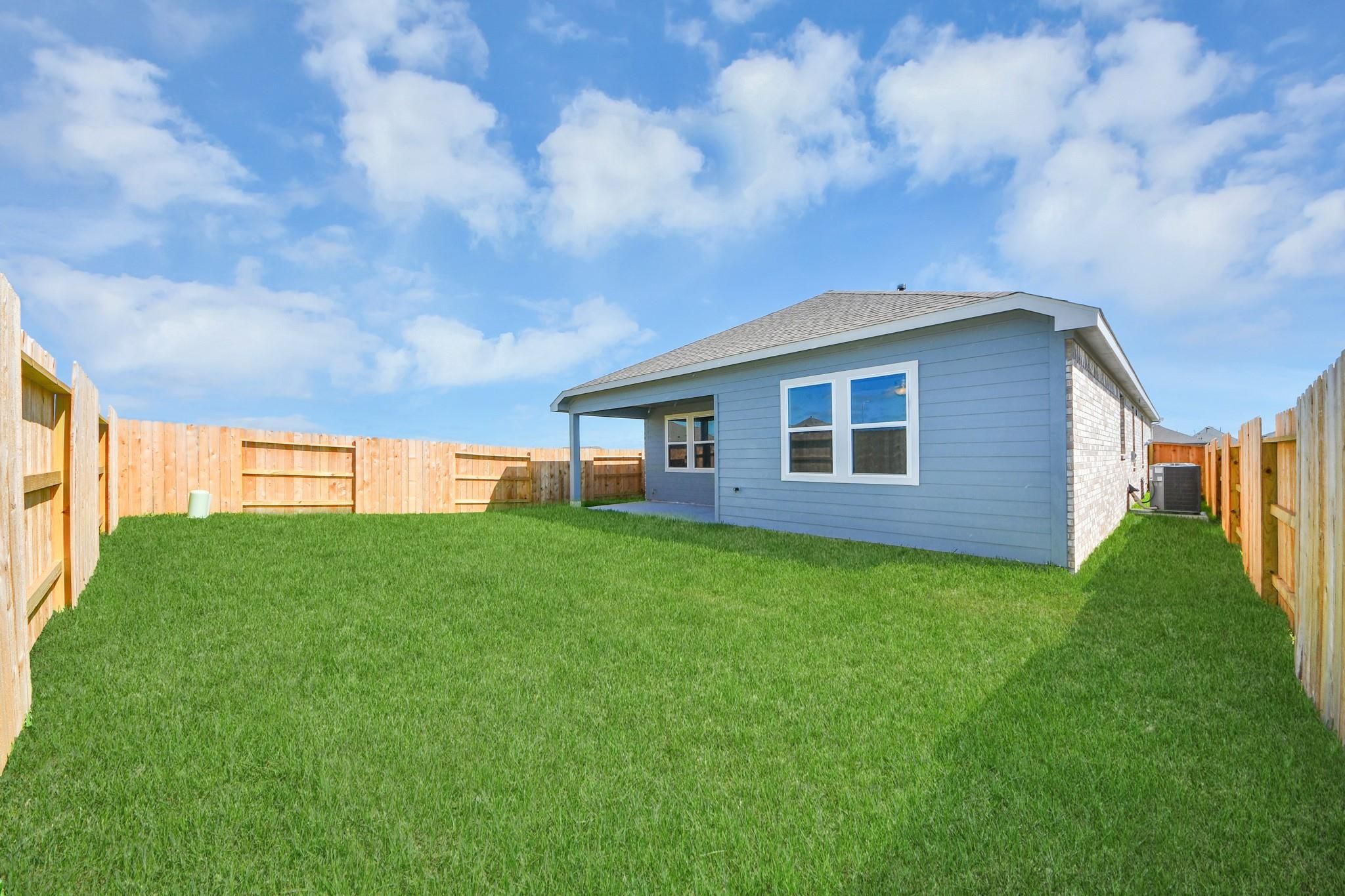 Spacious backyard with privacy fence and covered patio of The Riviera A home in Emberly, Beasley, Texas.