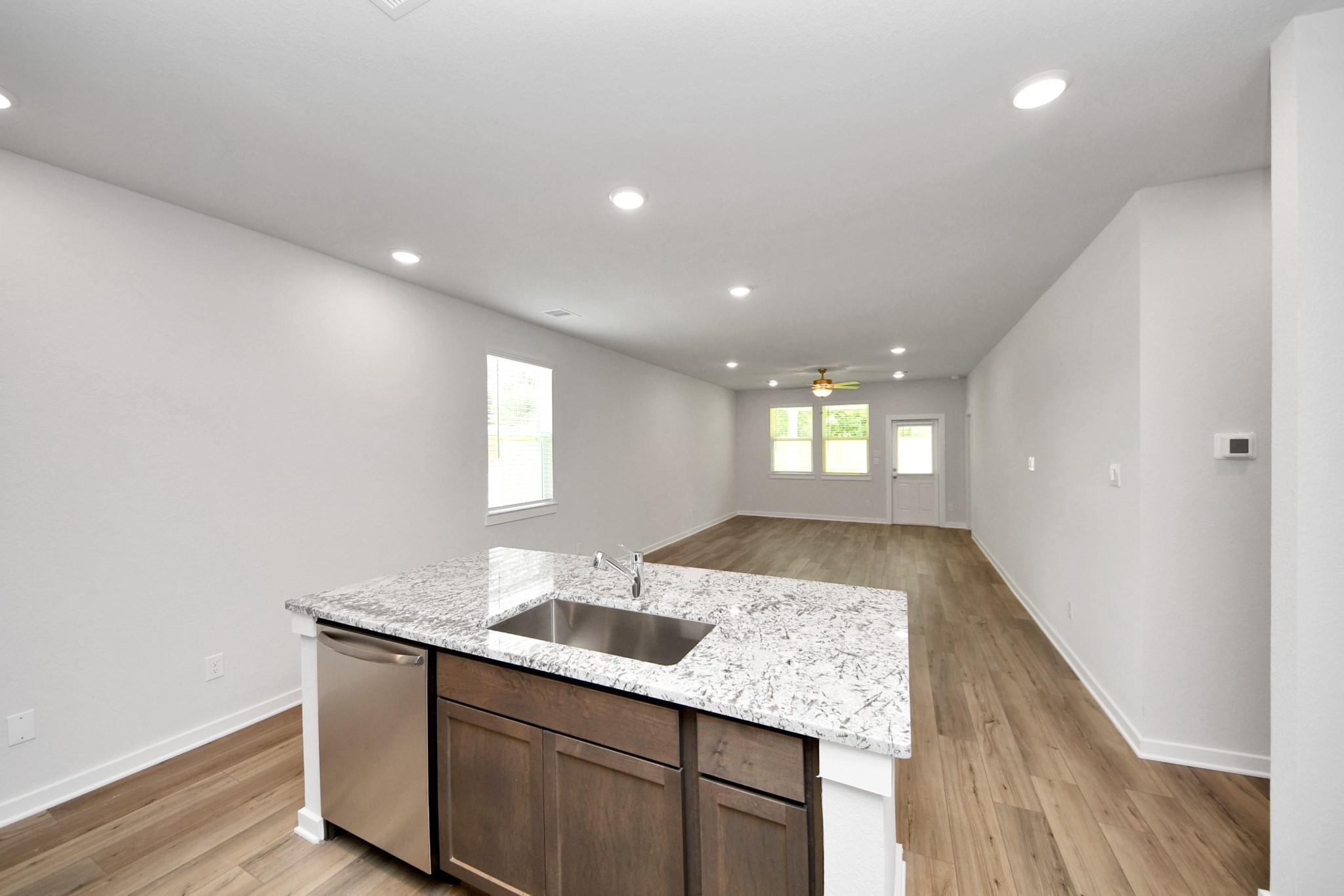 Open-concept kitchen with granite island in The Sabine E floor plan at Liberty Estates, Cleveland, Texas.