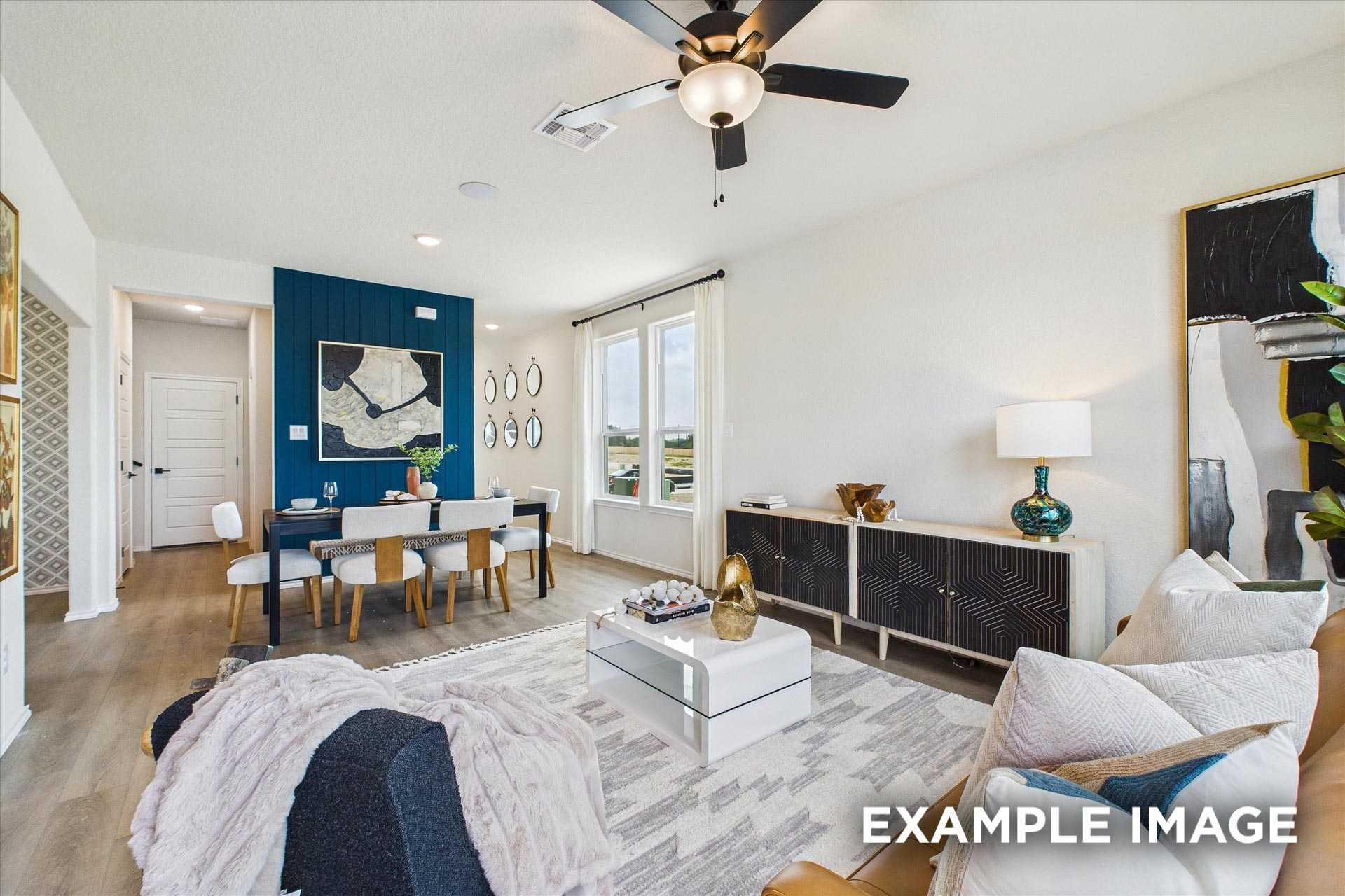 Modern dining room featuring navy accent wall, large windows, ceiling fan, and hardwood floors in The Florence C, San Antonio home