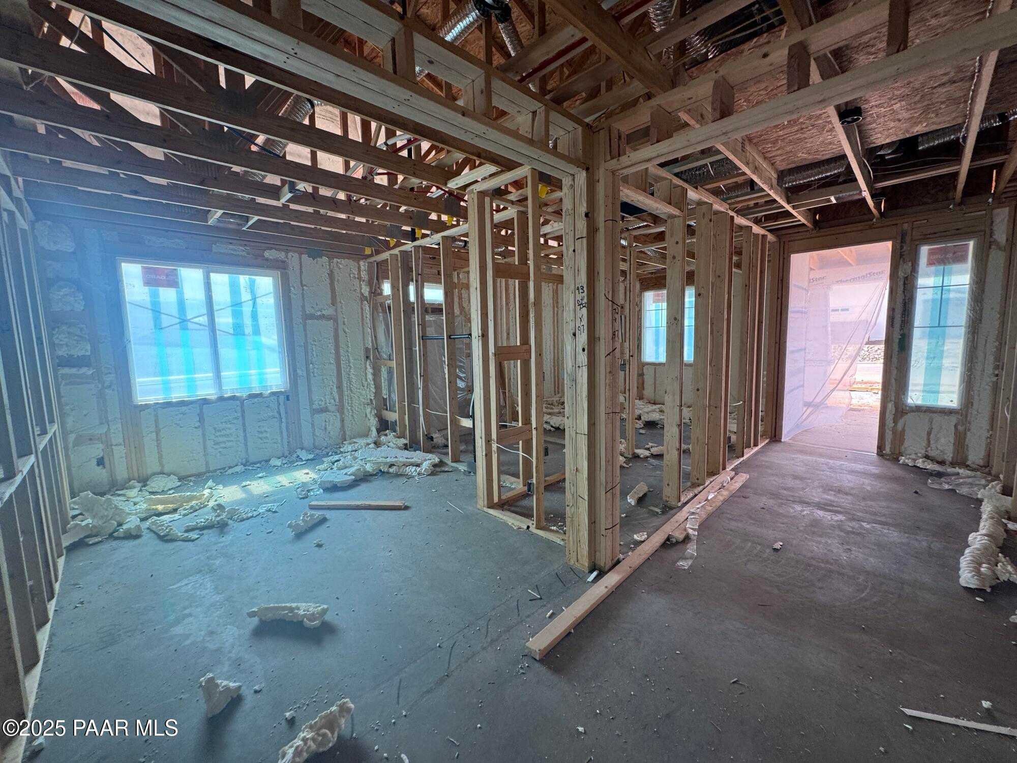 Wooden framed interior with wall insulation, large windows, and construction debris in The Sunrise A 3-bedroom home, Prescott Valley, Arizona