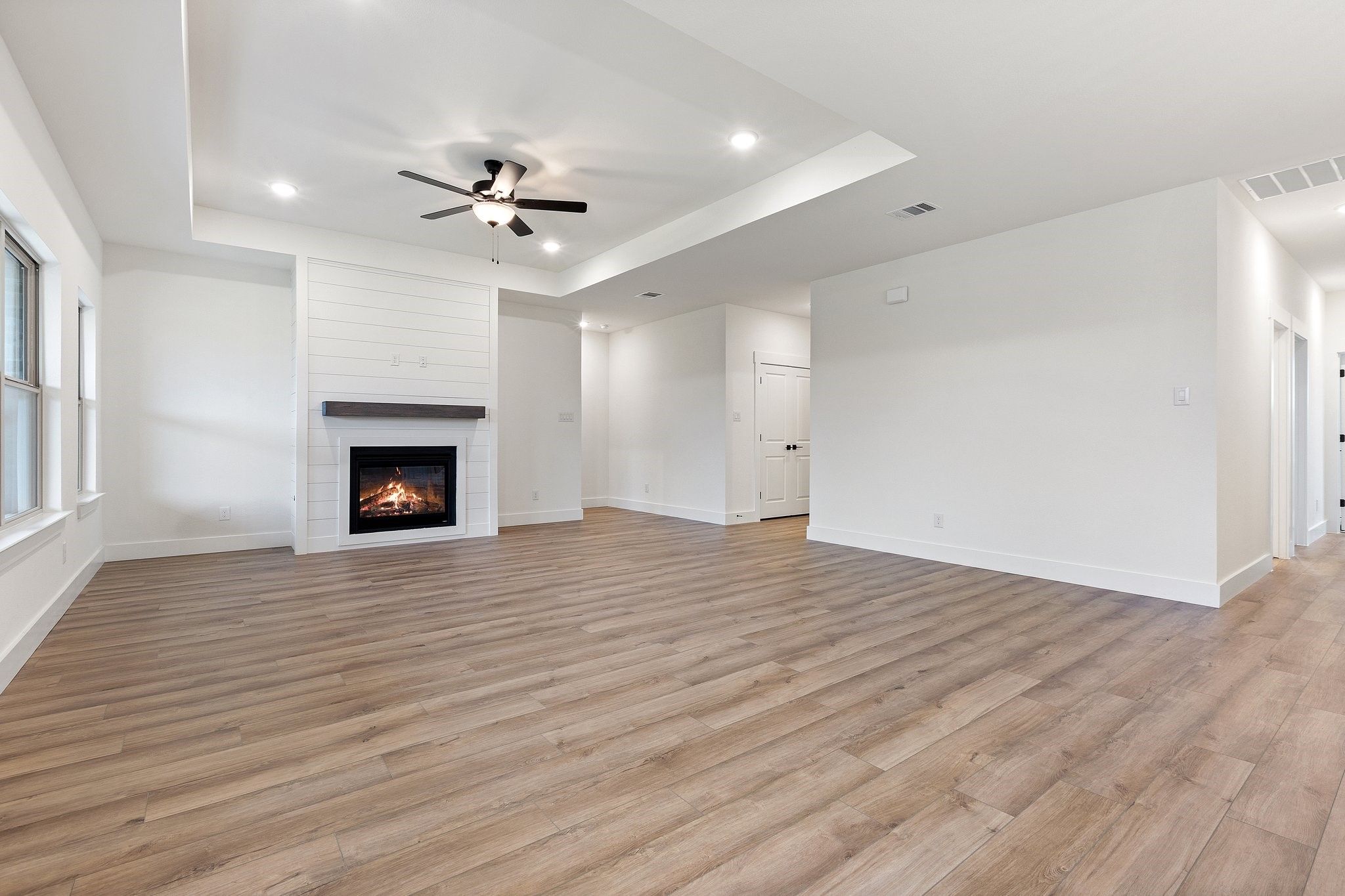 Spacious living room with tray ceiling and shiplap fireplace in The Rockford C home at Waverly Estates in Josephine, TX.